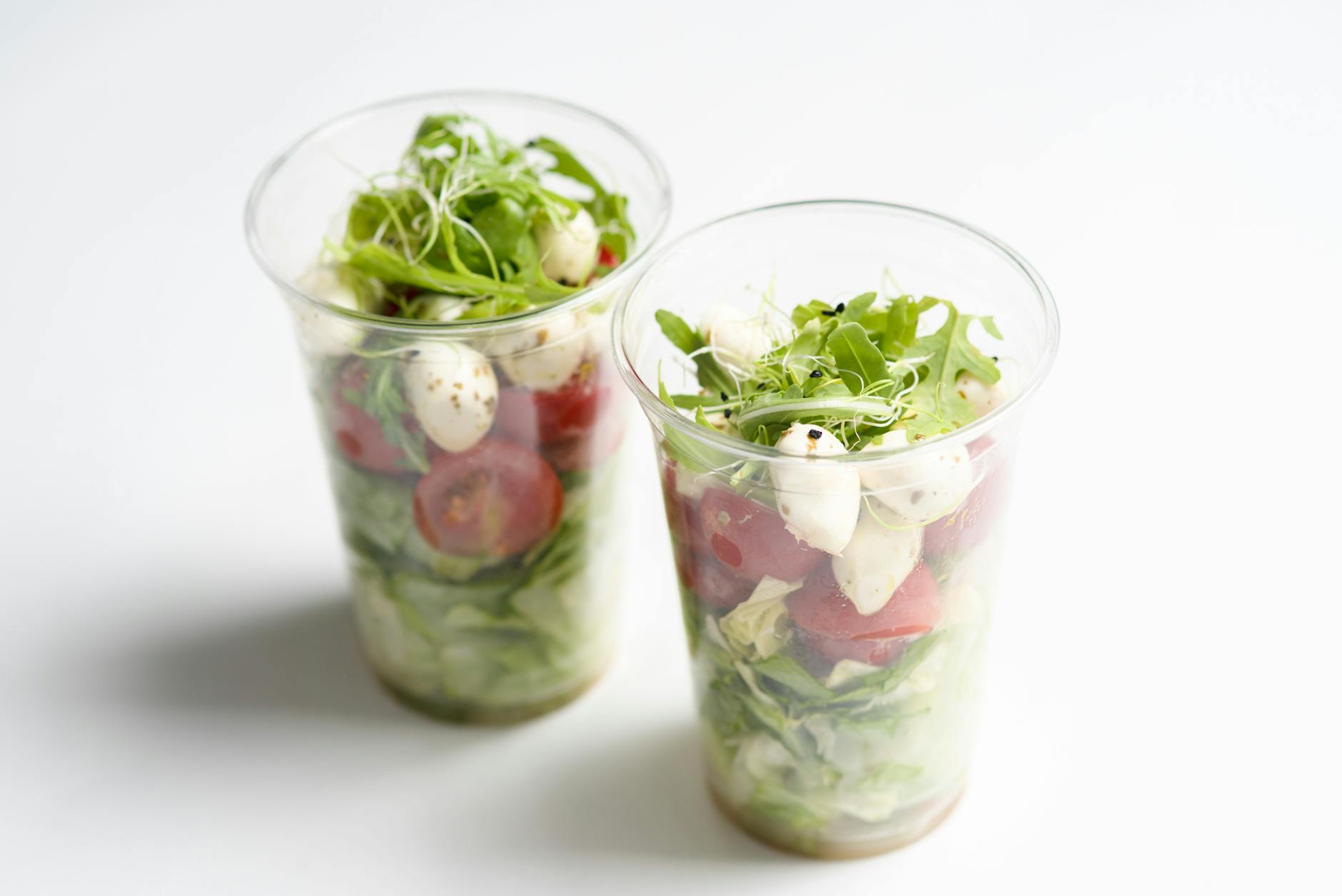 Healthy Caprese salad with mozzarella, tomatoes, and greens in plastic cups. Perfect for on-the-go meals. - quick lunch recipes