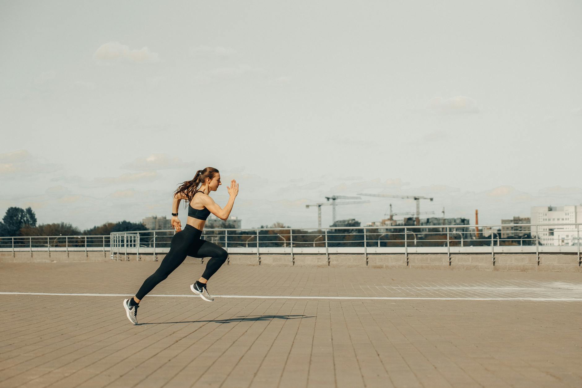 Woman sprinting on a rooftop in athletic wear during the day. - running plan for beginners