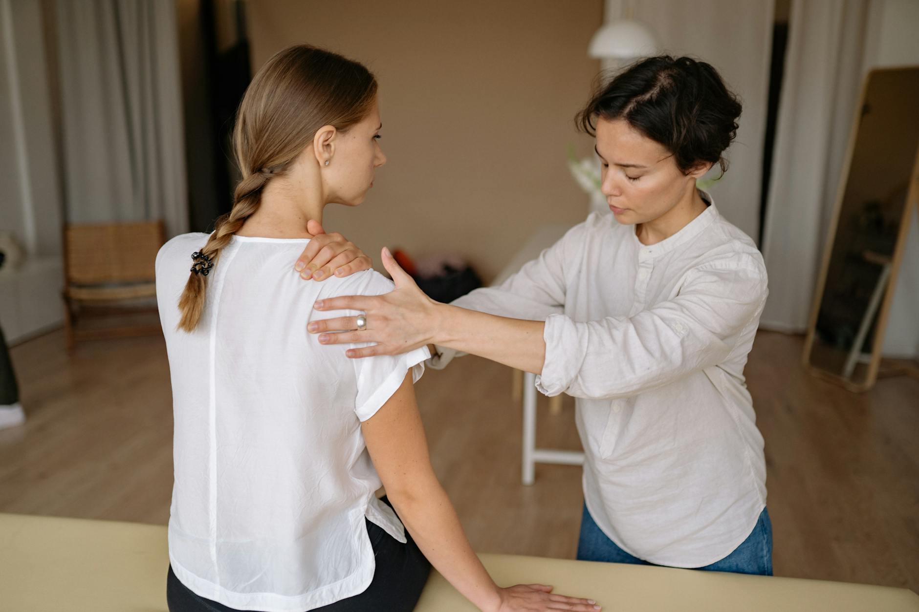 A therapist performing a shoulder massage on a woman to relieve physical tension. - shoulder pain relief