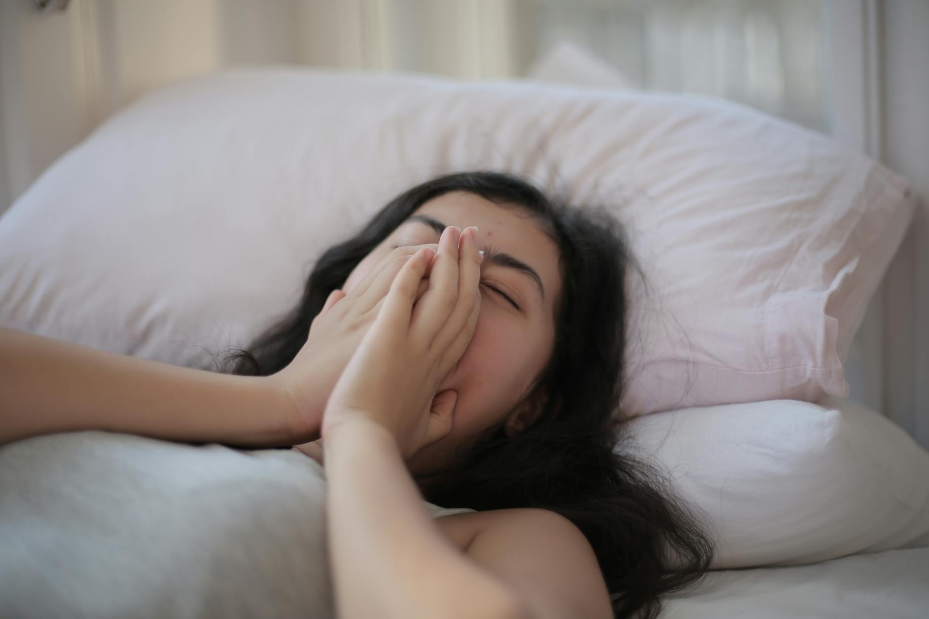 A serene scene of a woman resting in bed, displaying relaxation and comfort. - sleep deprivation causes
