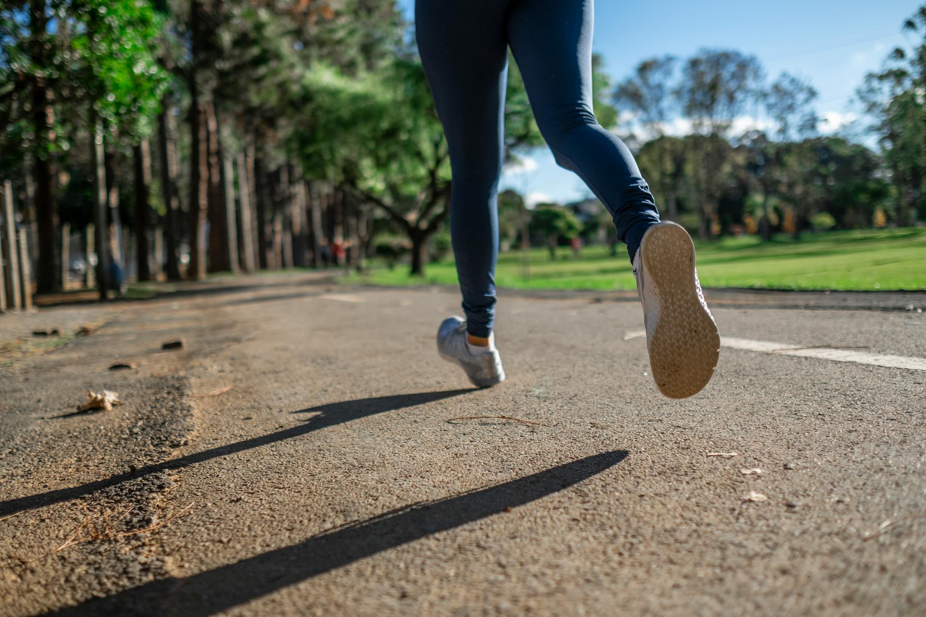 A woman running outdoors on a sunny day along a scenic park trail, focusing on fitness and health. - spring allergies exercise