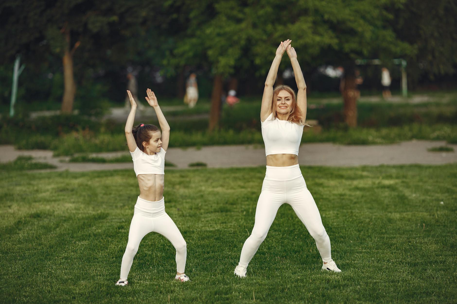 Mother and daughter in matching activewear doing exercises outdoors on a sunny day. - spring cardio fat burn