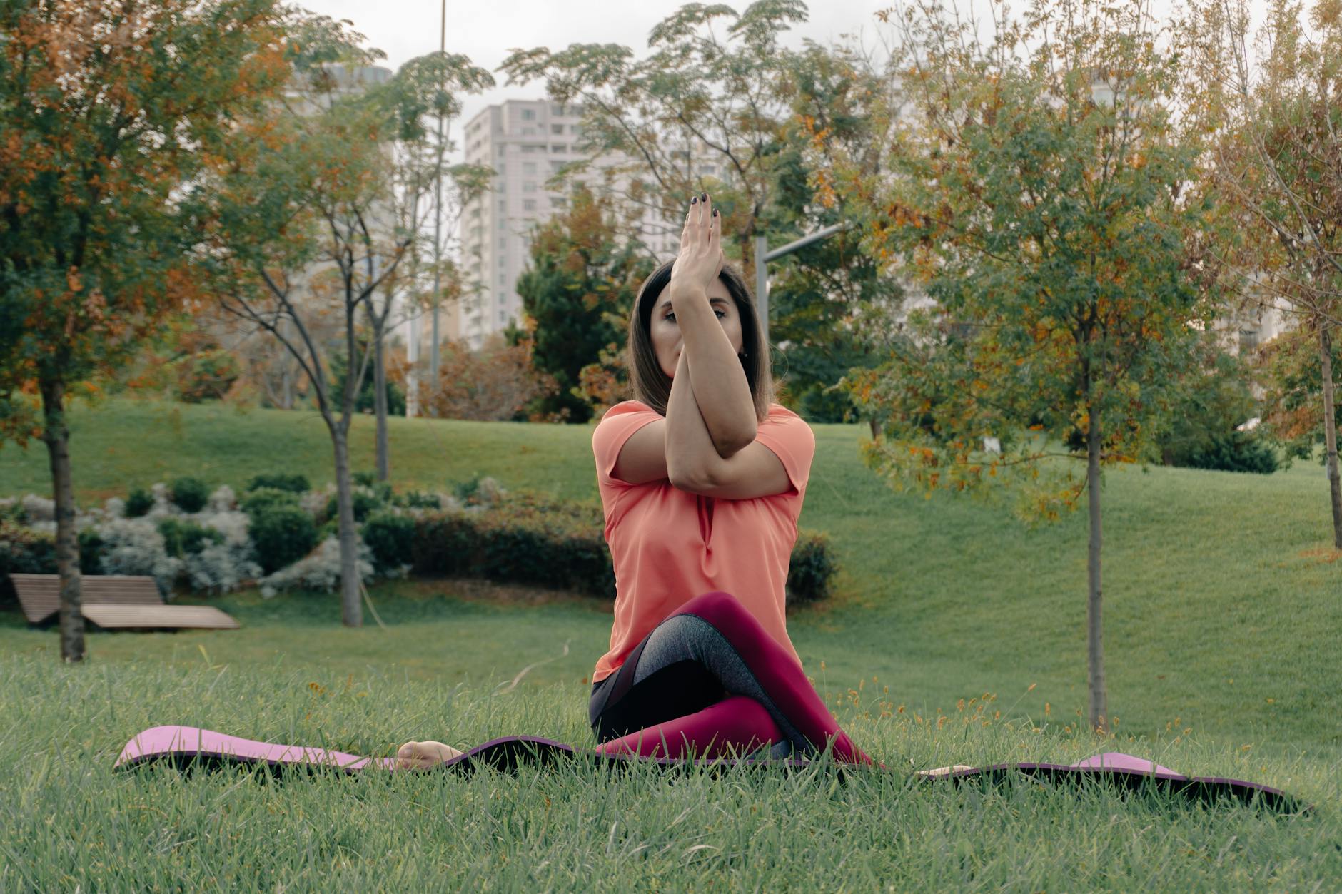 A woman performing a yoga pose on a mat in an urban park setting during fall. - spring outdoor exercise mental health