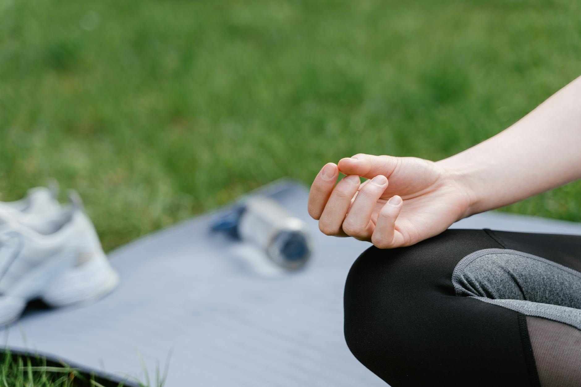 Close-up of a woman meditating outdoors on a mat. Focus on tranquility and mindfulness. - spring outdoor exercise mental health