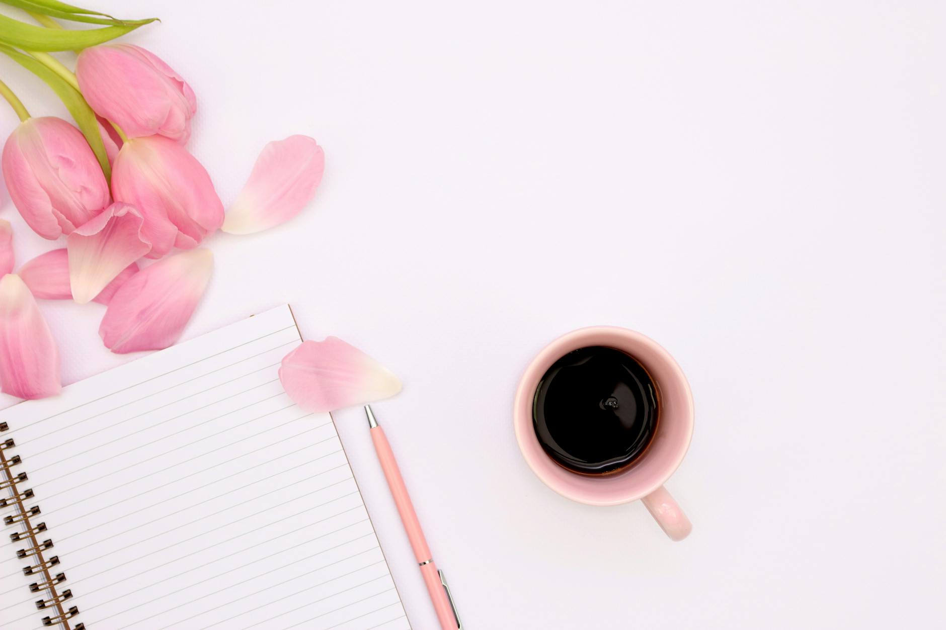 Aesthetic flat lay featuring a cup of coffee, pink tulips, and a spiral notebook. - spring reset journal prompts