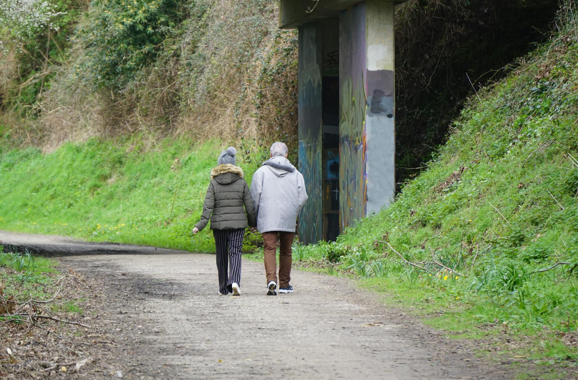 A couple enjoys a leisurely walk on a lush countryside path surrounded by greenery. - spring walking plan