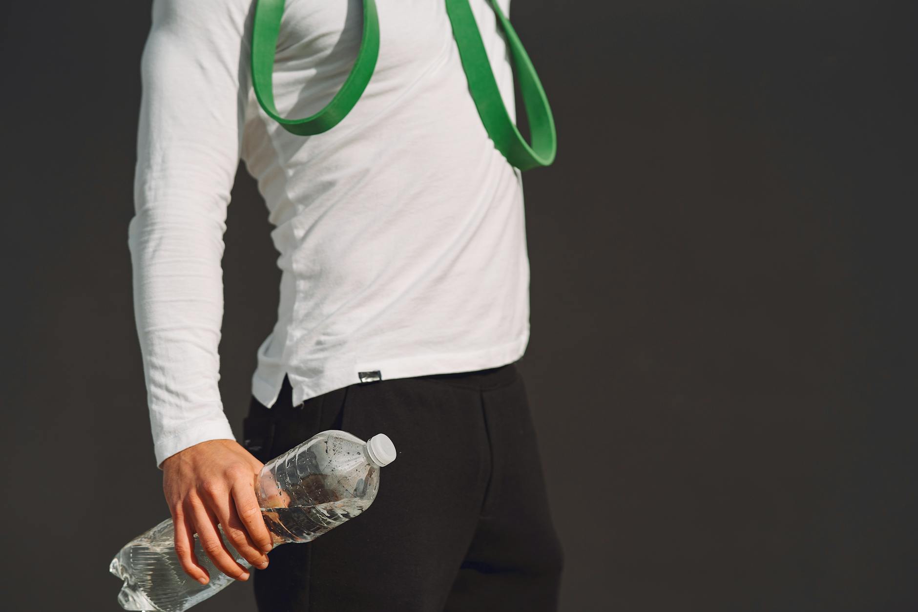 An individual holds a water bottle and fitness band, showcasing a healthy lifestyle and exercise readiness. - spring workout hydration