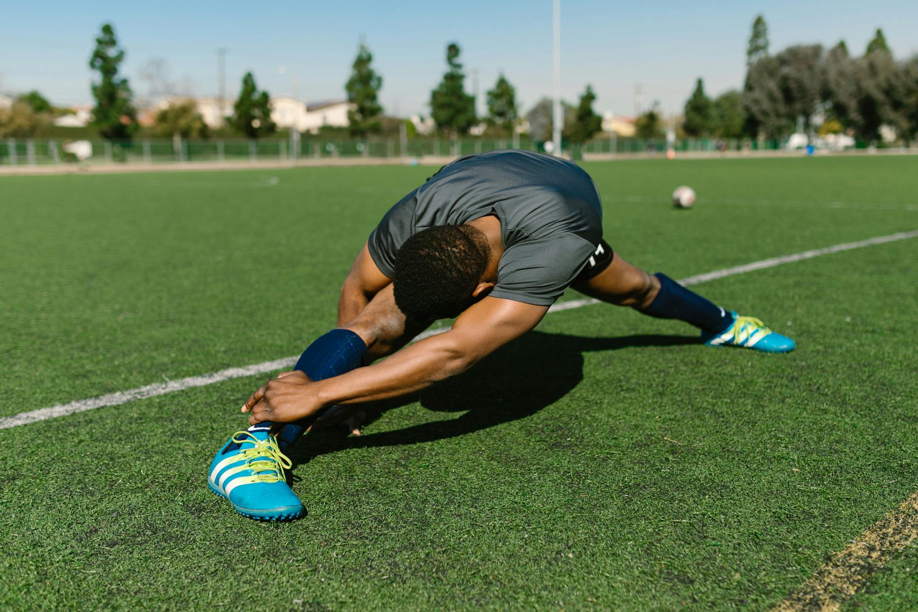 Black male athlete stretching on a soccer field, showcasing flexibility and athleticism. - static stretching benefits