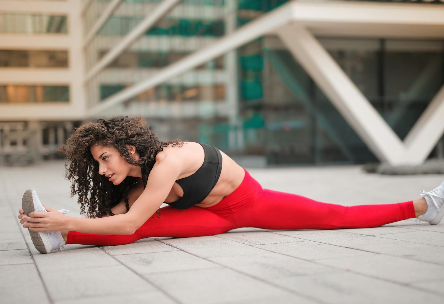A woman performs a stretching exercise in an urban environment, showcasing flexibility and fitness. - static stretching benefits
