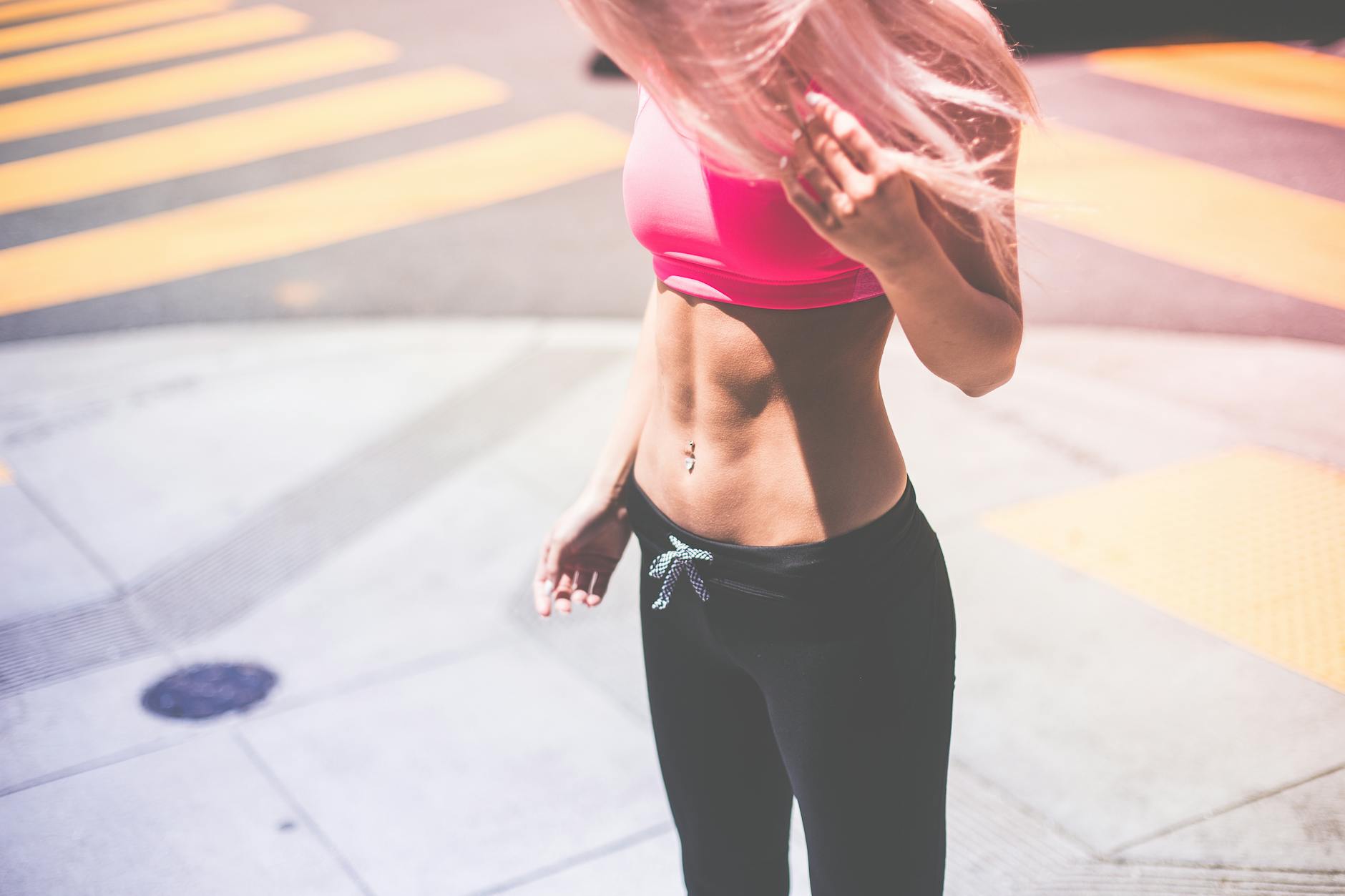 Athletic woman in pink activewear showing toned abs in urban San Francisco setting. - stomach fat workout