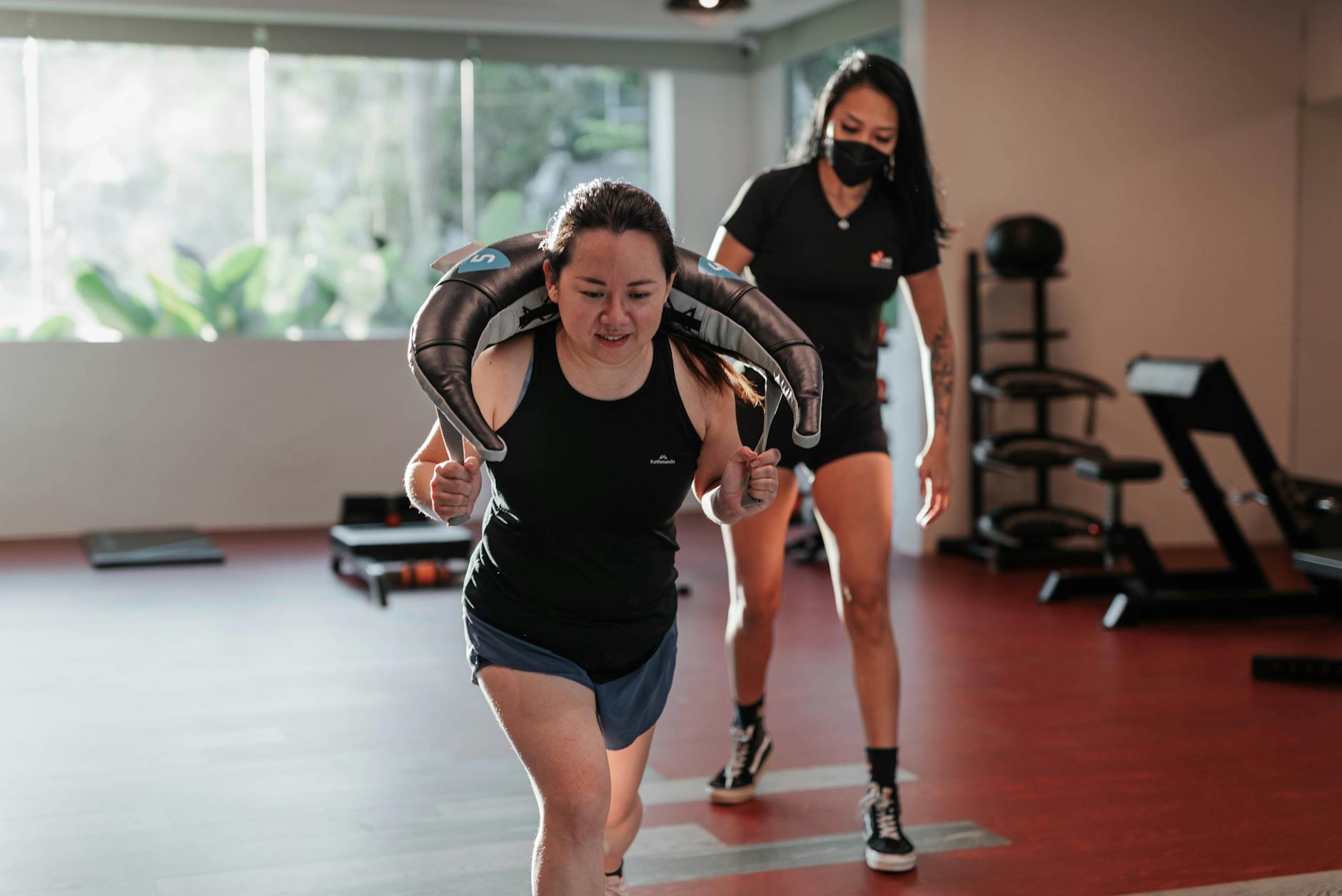 Two women focused on strength training in a Singapore gym with a personal trainer. - strength training for women