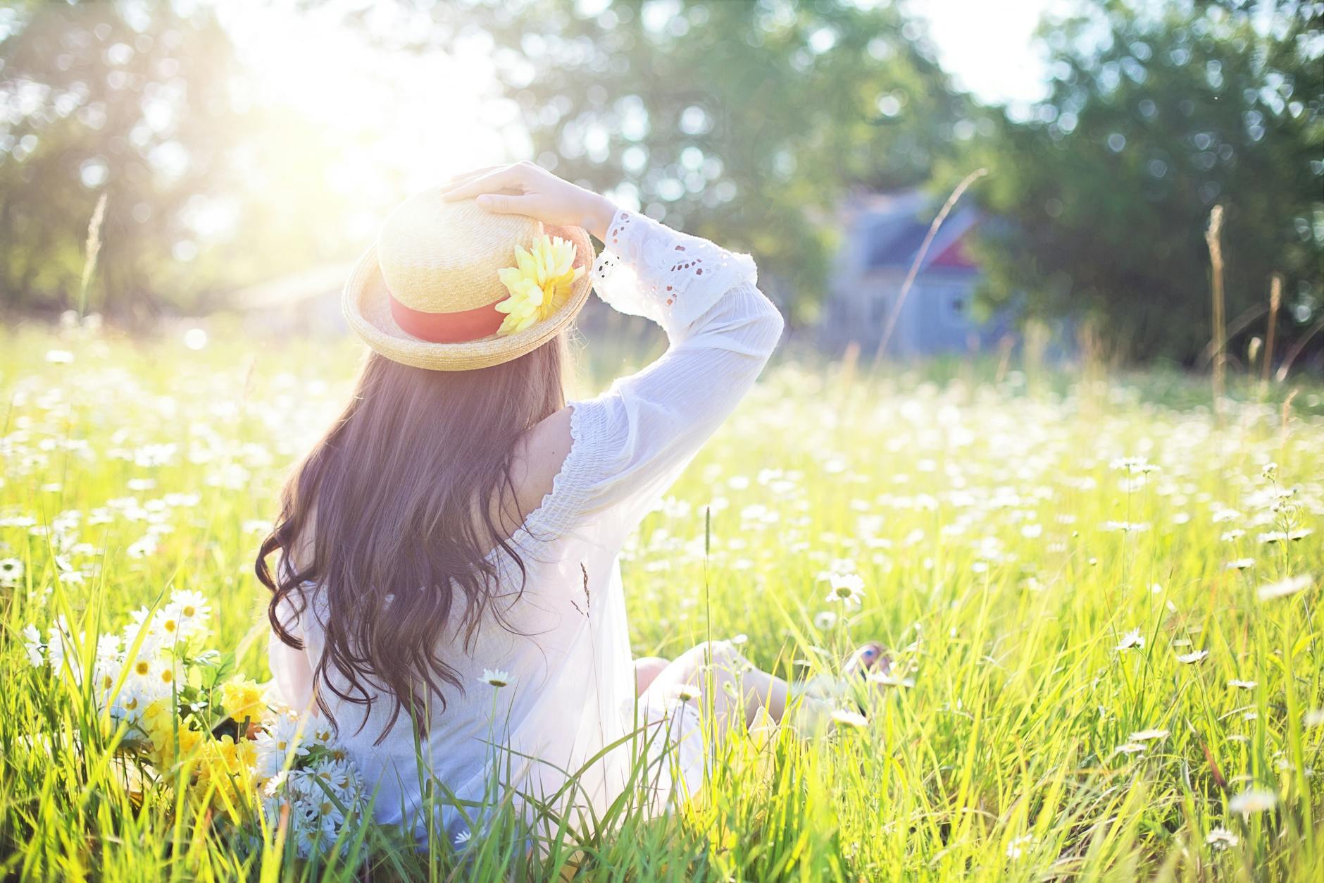 Woman in a straw hat sitting in a sunlit meadow filled with white flowers. - sunlight weight loss