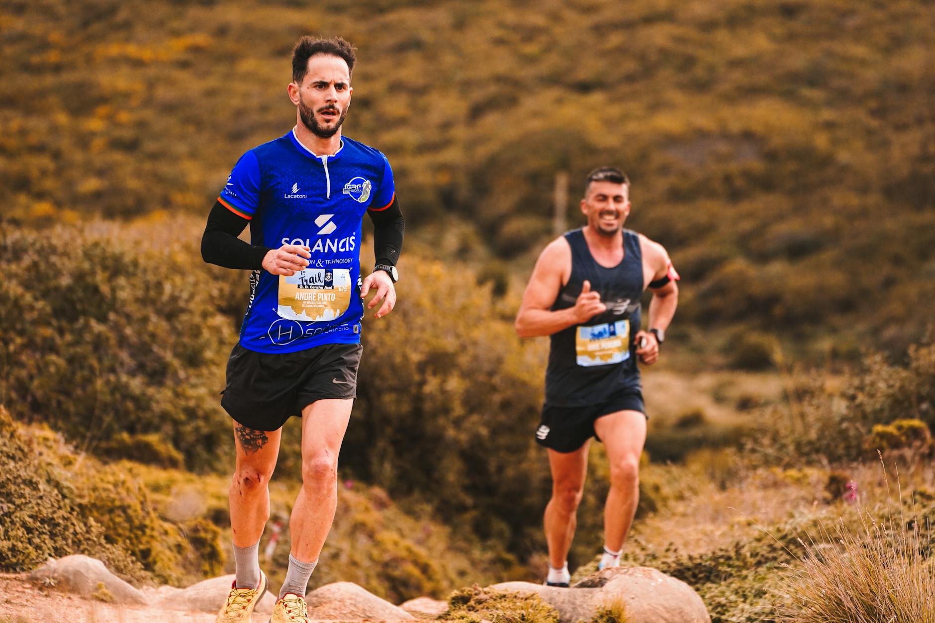Dynamic image of two men trail running through an outdoor natural setting, showcasing energy and fitness. - trail running advanced
