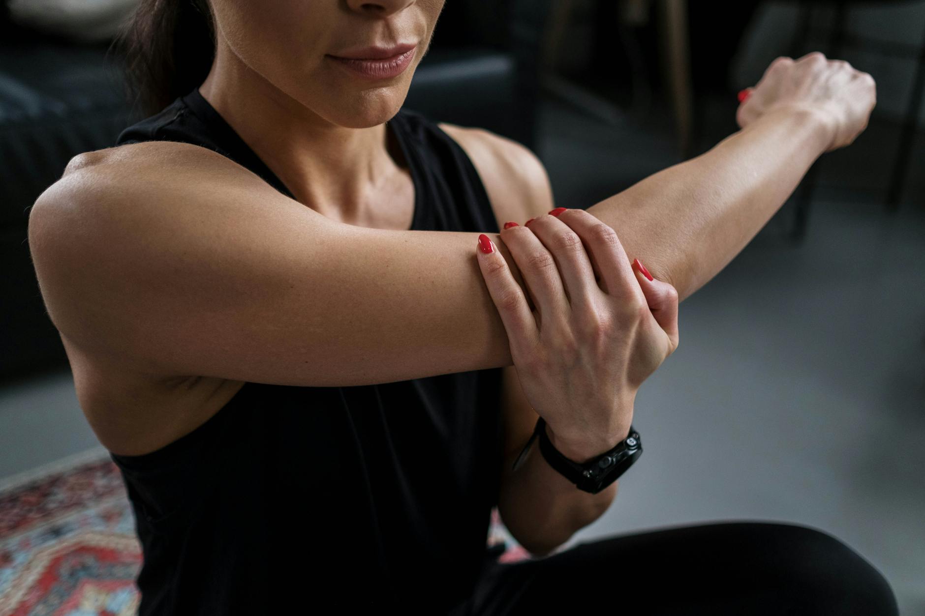 Close-up of a woman stretching her arm indoors during a fitness routine. - upper body stretches