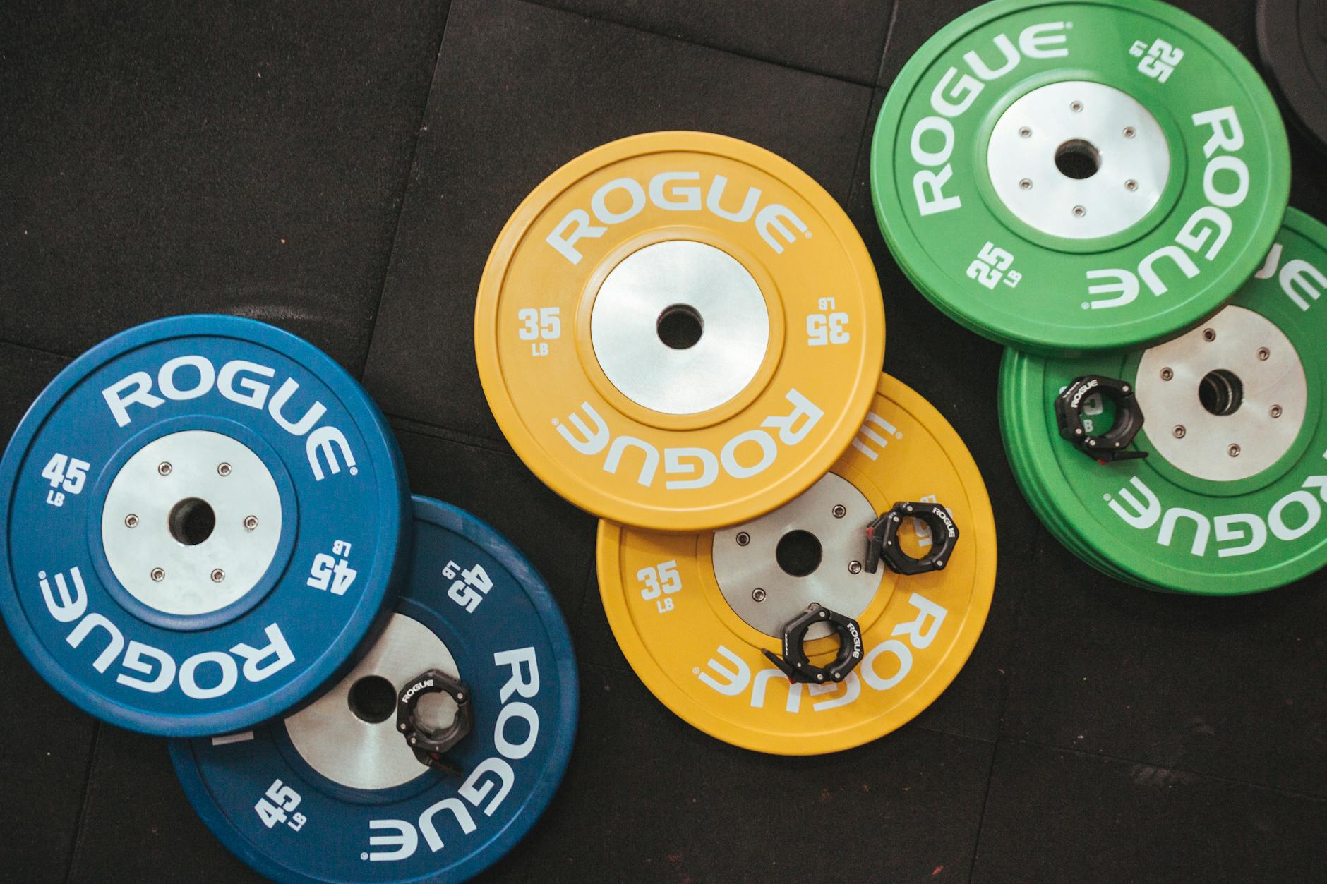 Colorful Rogue weight plates arranged on a gym floor visualizing fitness and strength. - weight training benefits