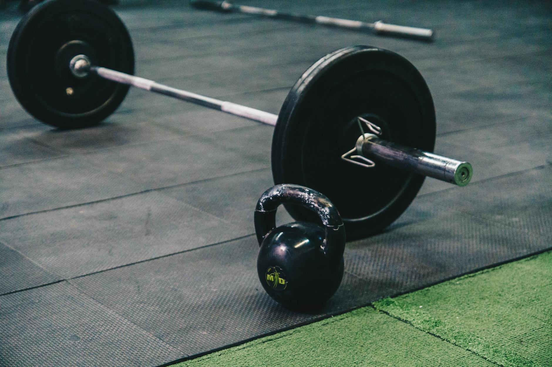 Barbell and kettlebell on gym floor, ideal for fitness and strength training themes. - weight training benefits
