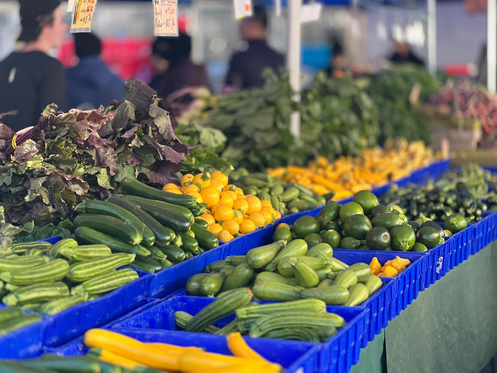 Colorful array of fresh vegetables in baskets at an outdoor farmers market. - winter produce reset