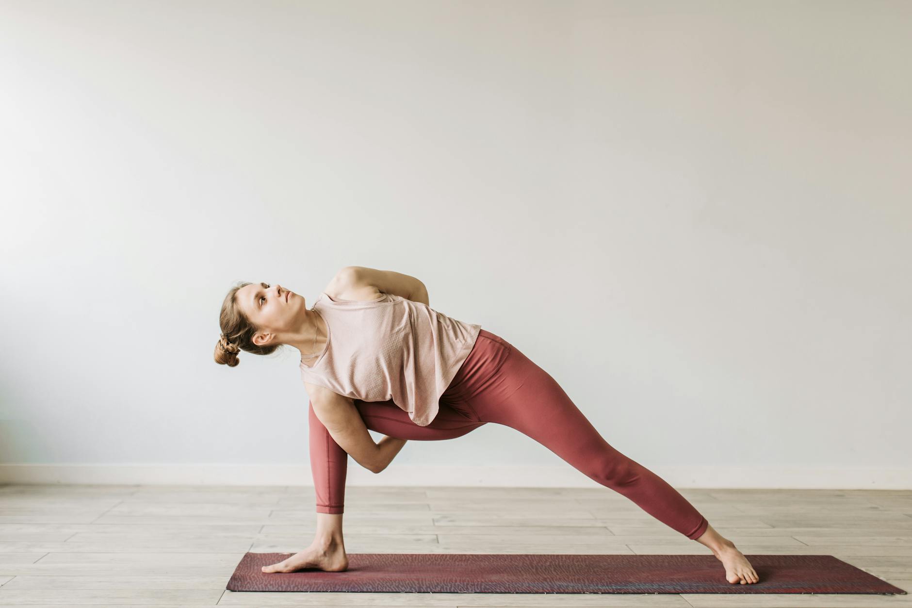 A woman practicing a yoga pose indoors on a mat, showcasing flexibility and wellness. - yoga poses for beginners
