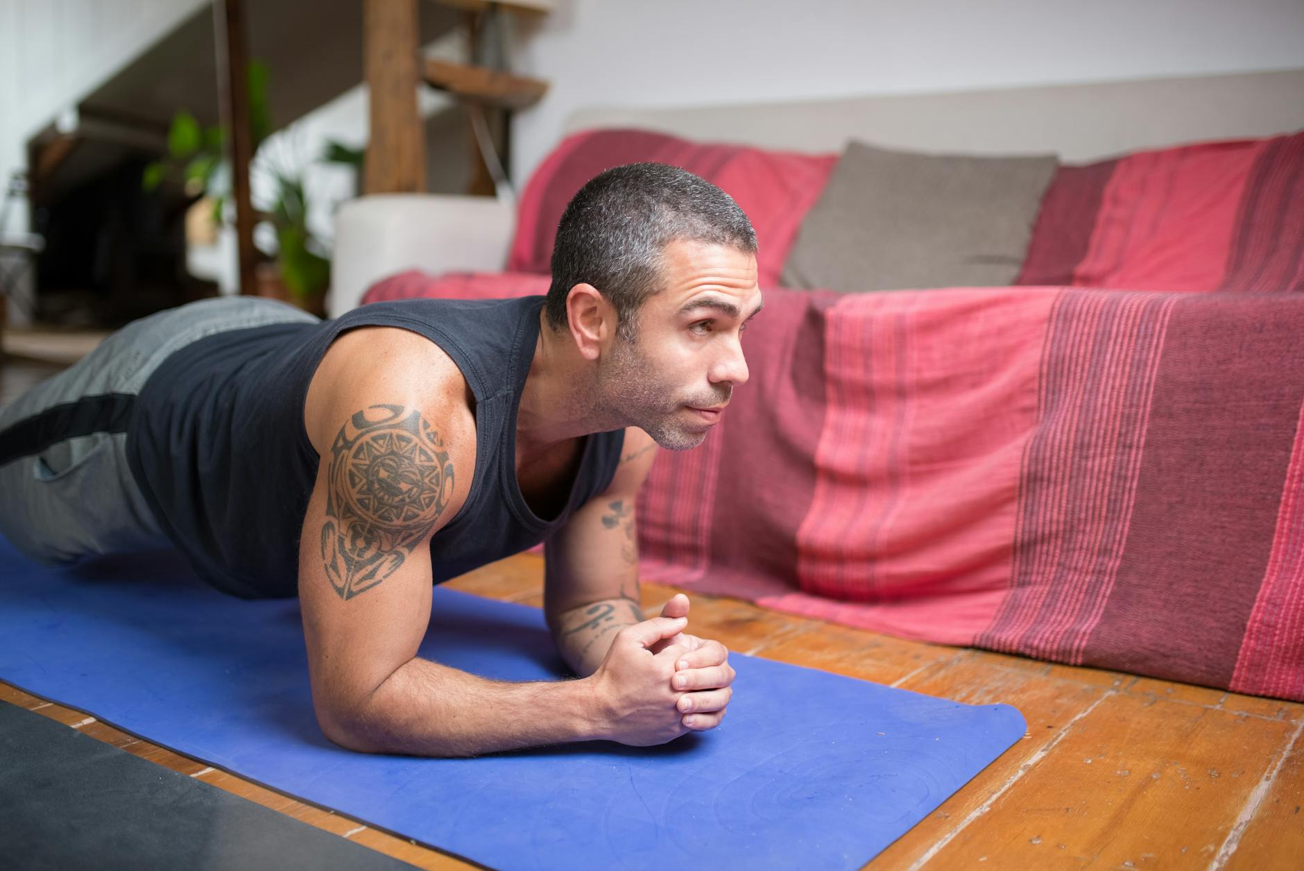 Man doing plank exercise indoors on a yoga mat, embracing a healthy lifestyle. - advanced core exercises