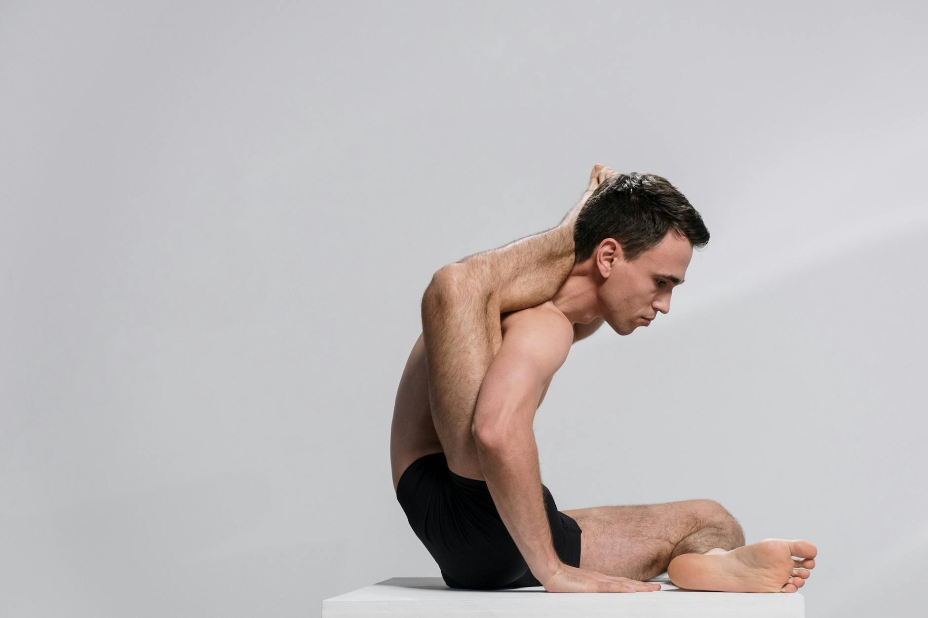 A man demonstrating an advanced yoga pose indoors, showcasing flexibility and concentration. - advanced yoga flexibility
