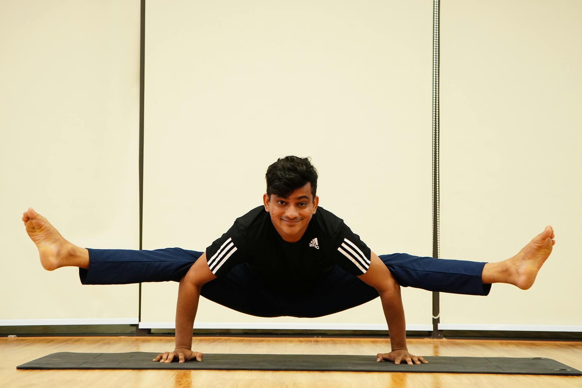 Adult man practicing an advanced yoga pose on a mat indoors, showcasing balance and strength. - advanced yoga flexibility