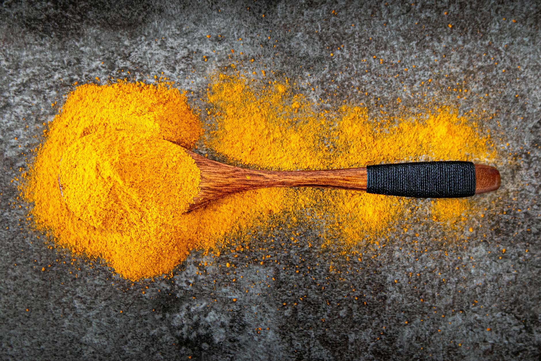 Vibrant turmeric powder spread with a wooden spoon for cooking inspiration. - anti-inflammatory foods spring allergies
