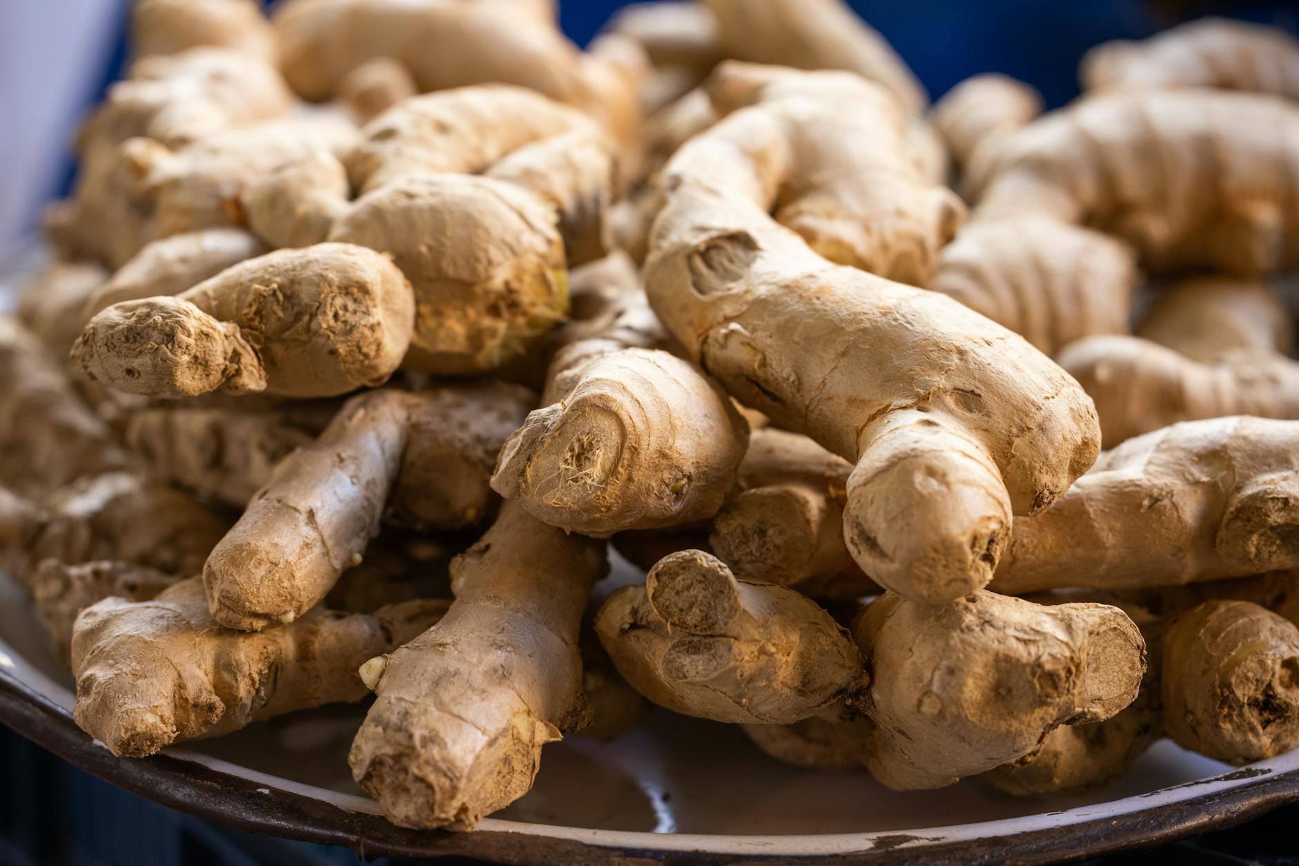 A close-up photo of fresh, raw ginger roots piled on a plate. Perfect for culinary use. - anti-inflammatory foods spring allergies