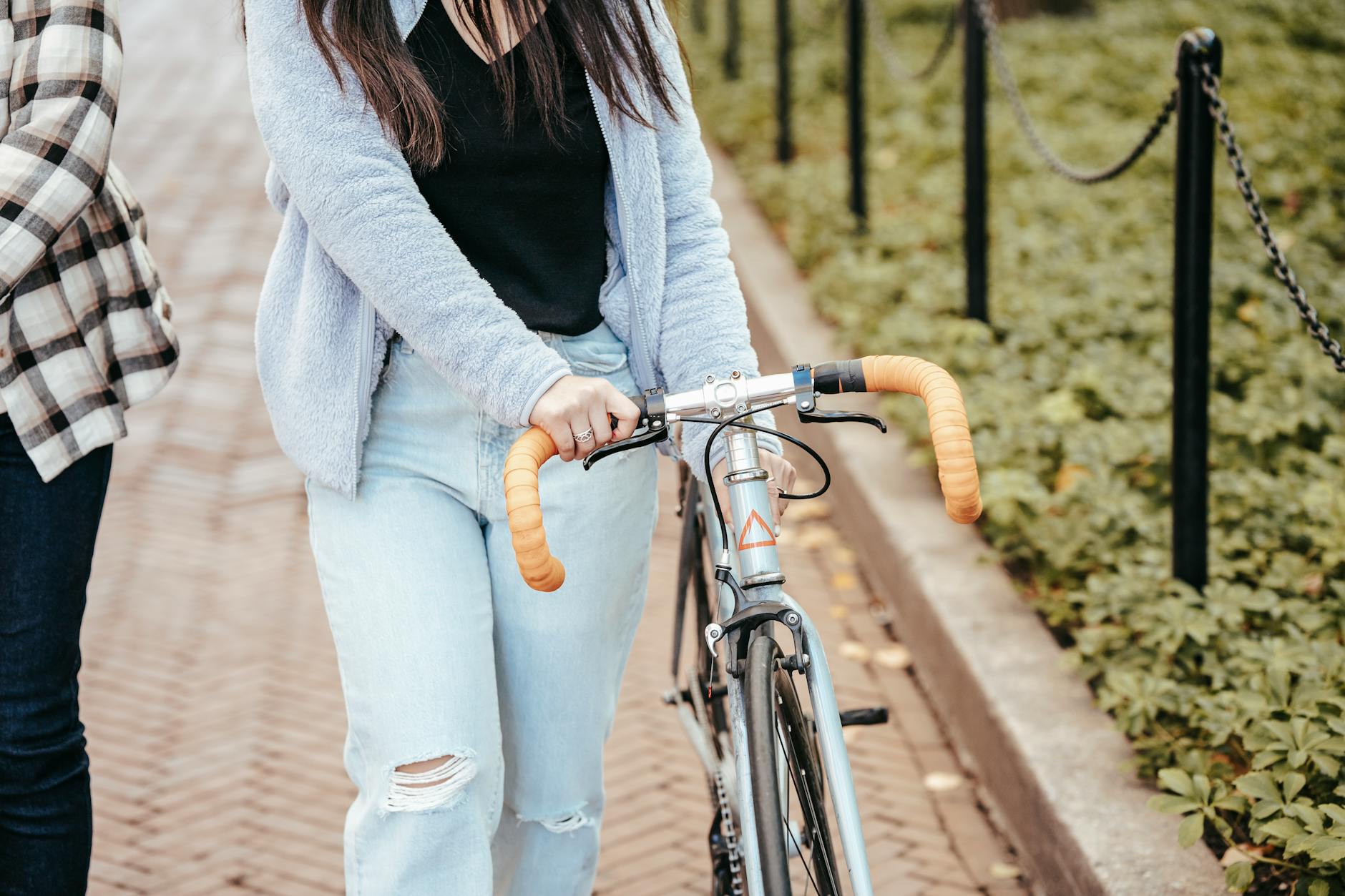 Crop faceless female in casual outfit strolling with bicycle near girlfriend while spending free time in park - beginner bike rides spring