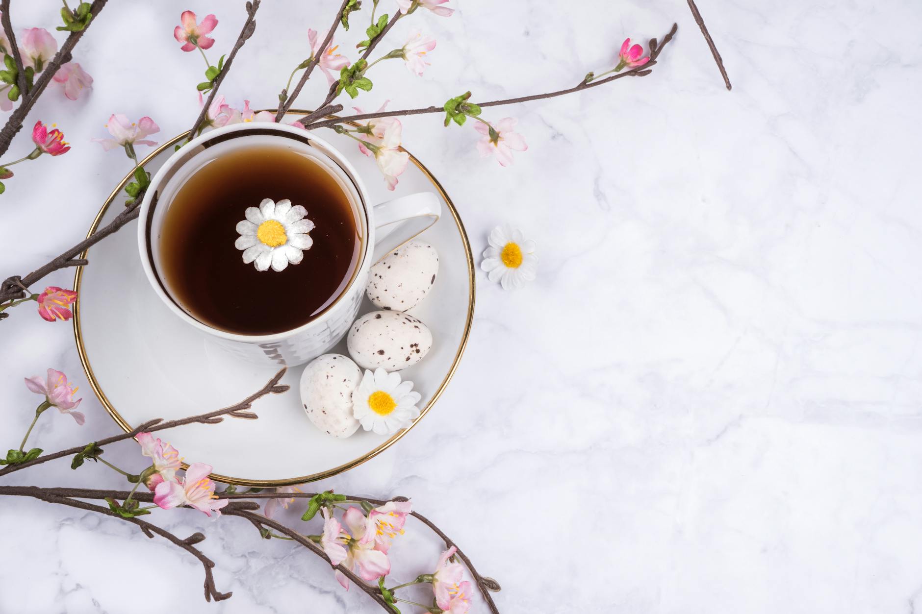 Cup of tea with cherry blossoms and Easter eggs on marble surface. - bloating relief spring