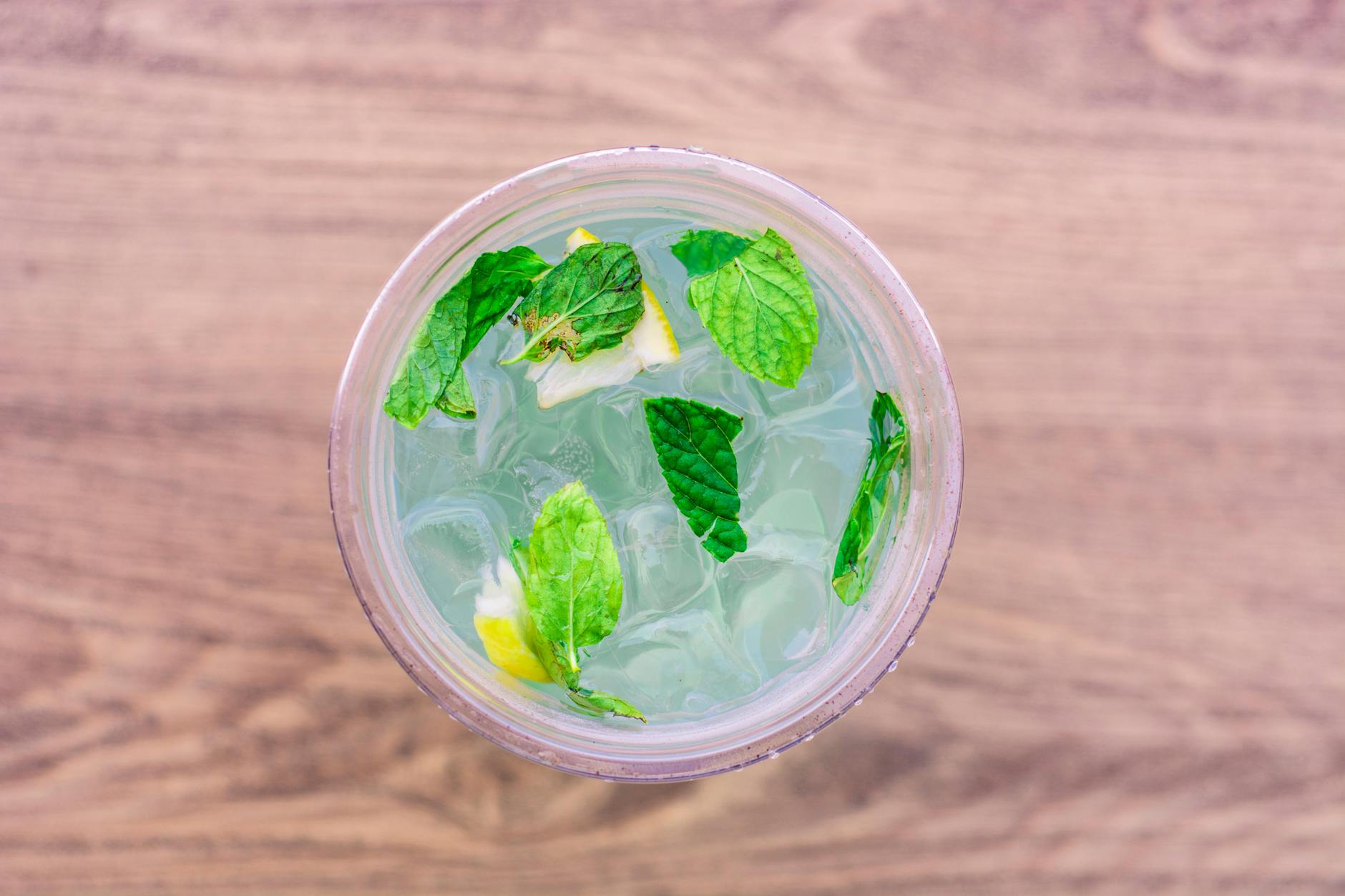 A refreshing iced drink with lemon and mint leaves viewed from above. - bloating relief spring