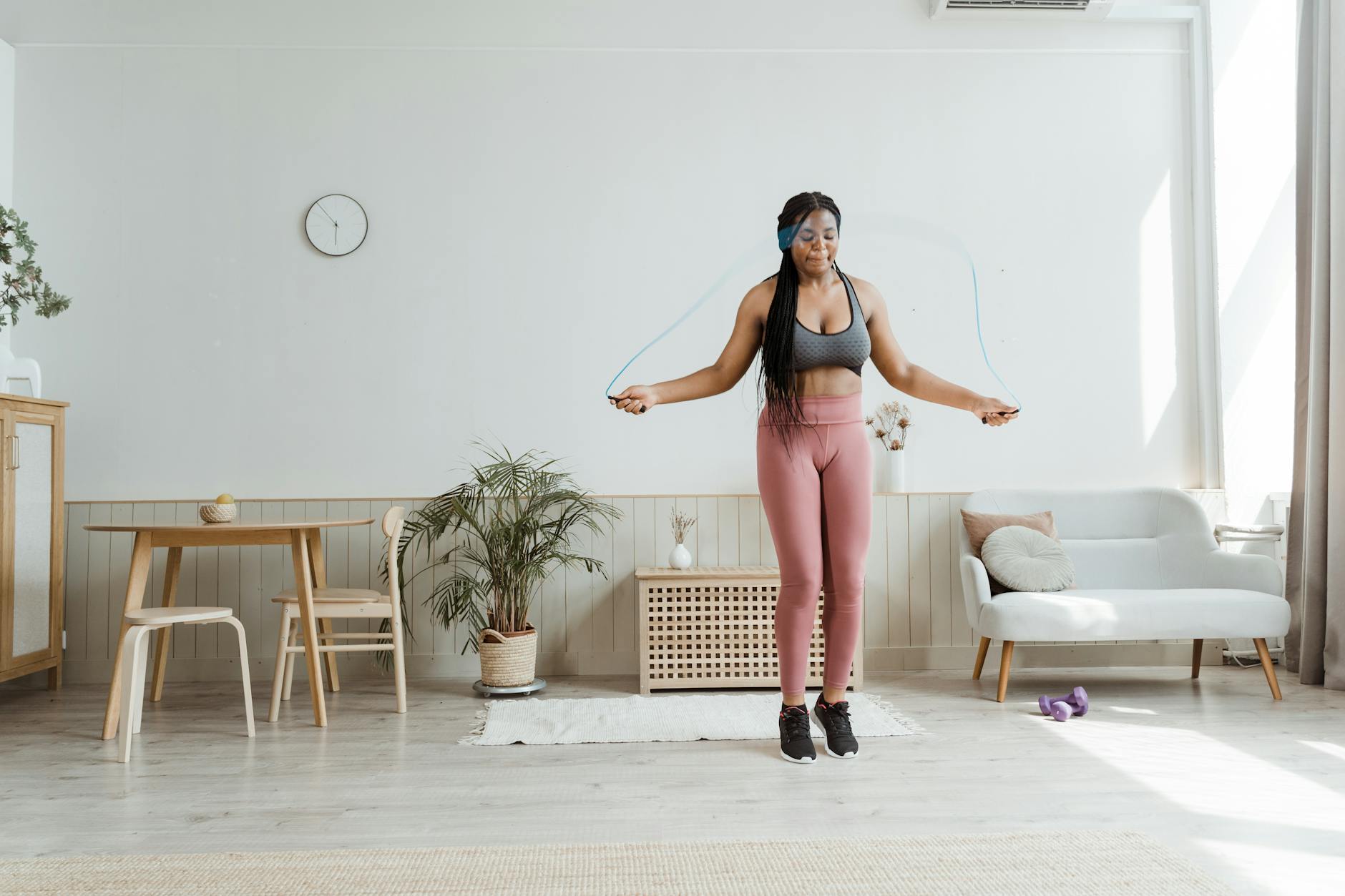 Confident black woman in activewear jump roping at home, promoting wellness and body positivity. - cardio for weight loss