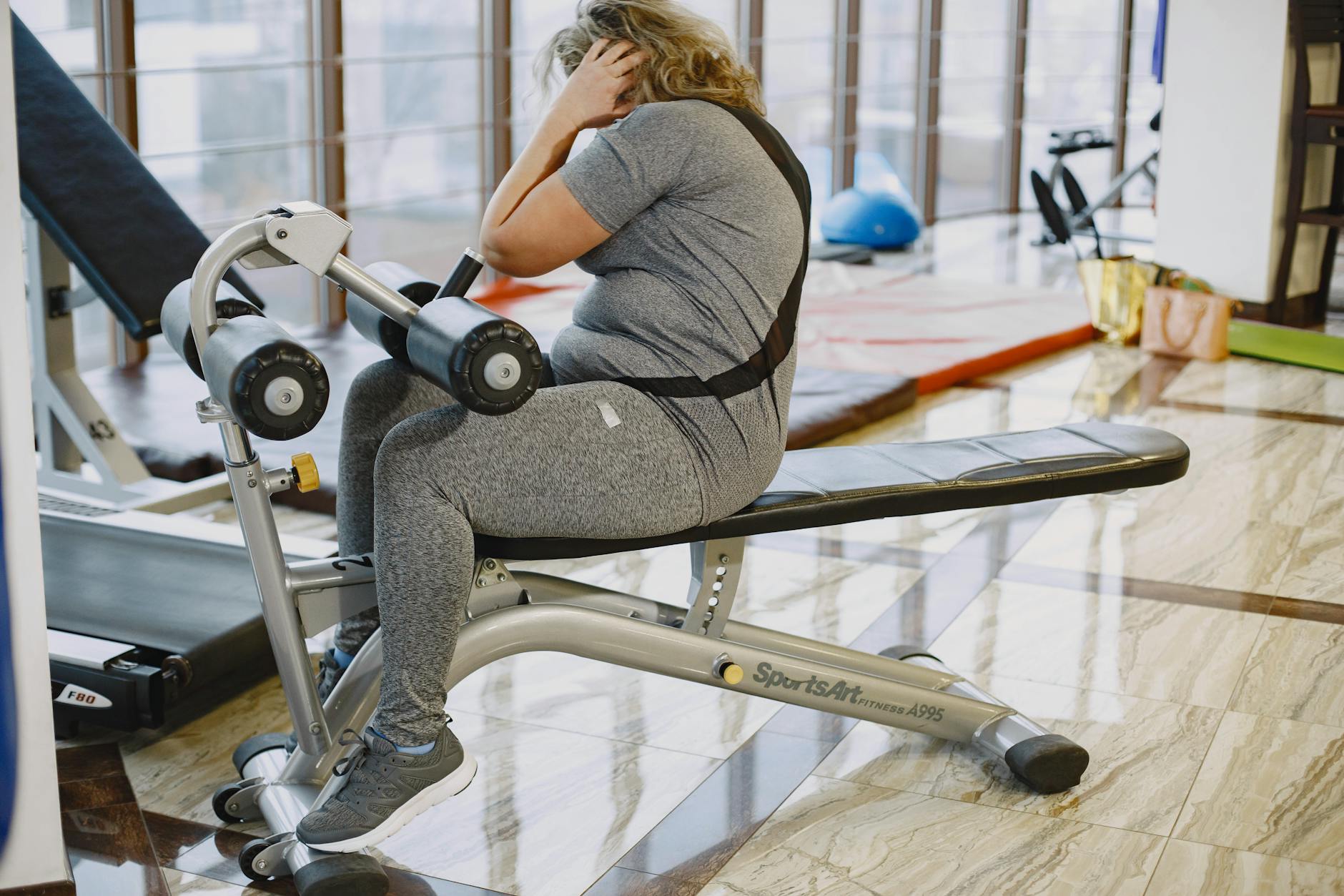 Woman performing sit-ups on gym equipment, promoting fitness and healthy lifestyle. - cardio for weight loss