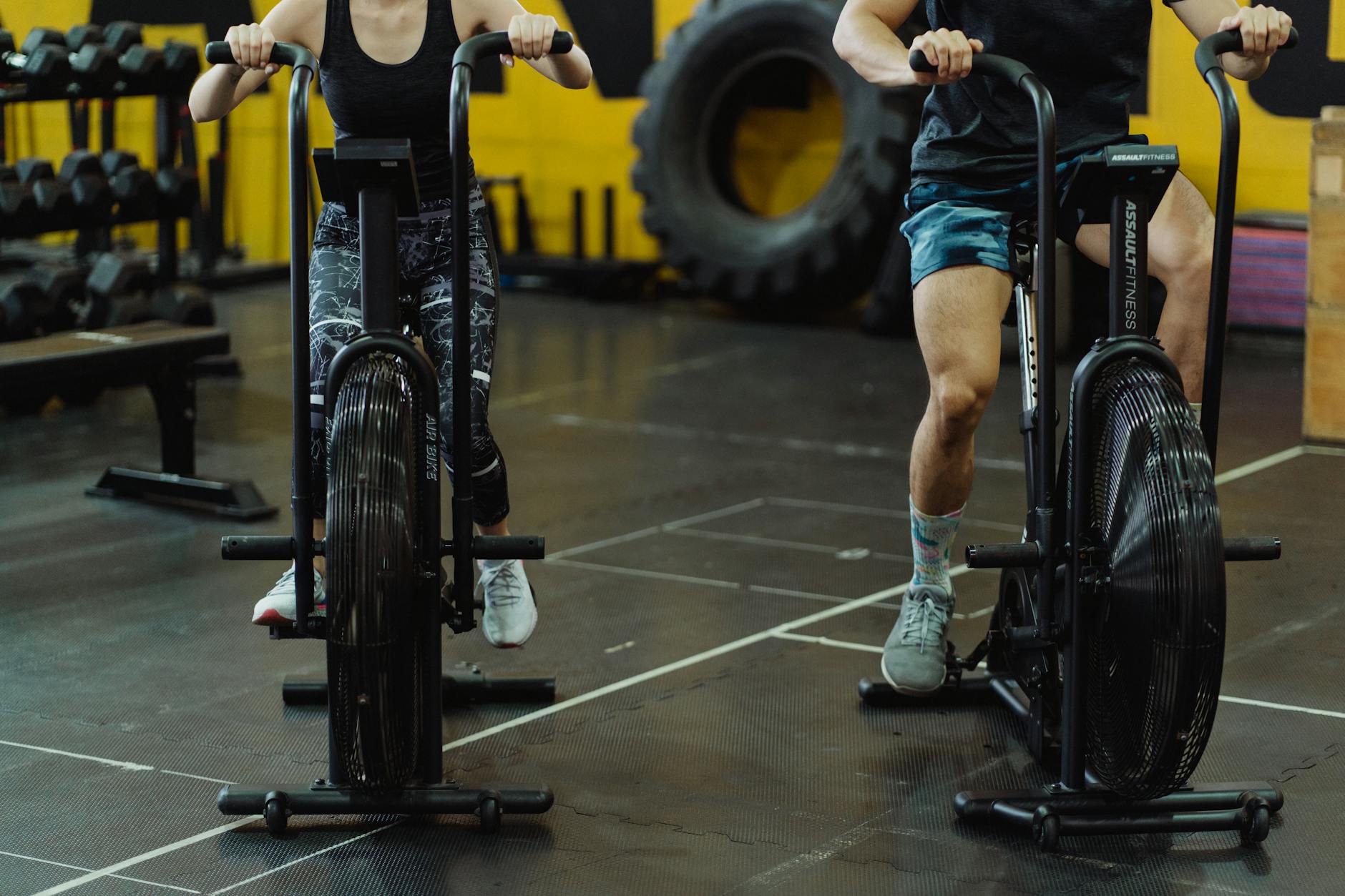 Two people exercising on stationary bikes at a modern gym. - may cardio workouts