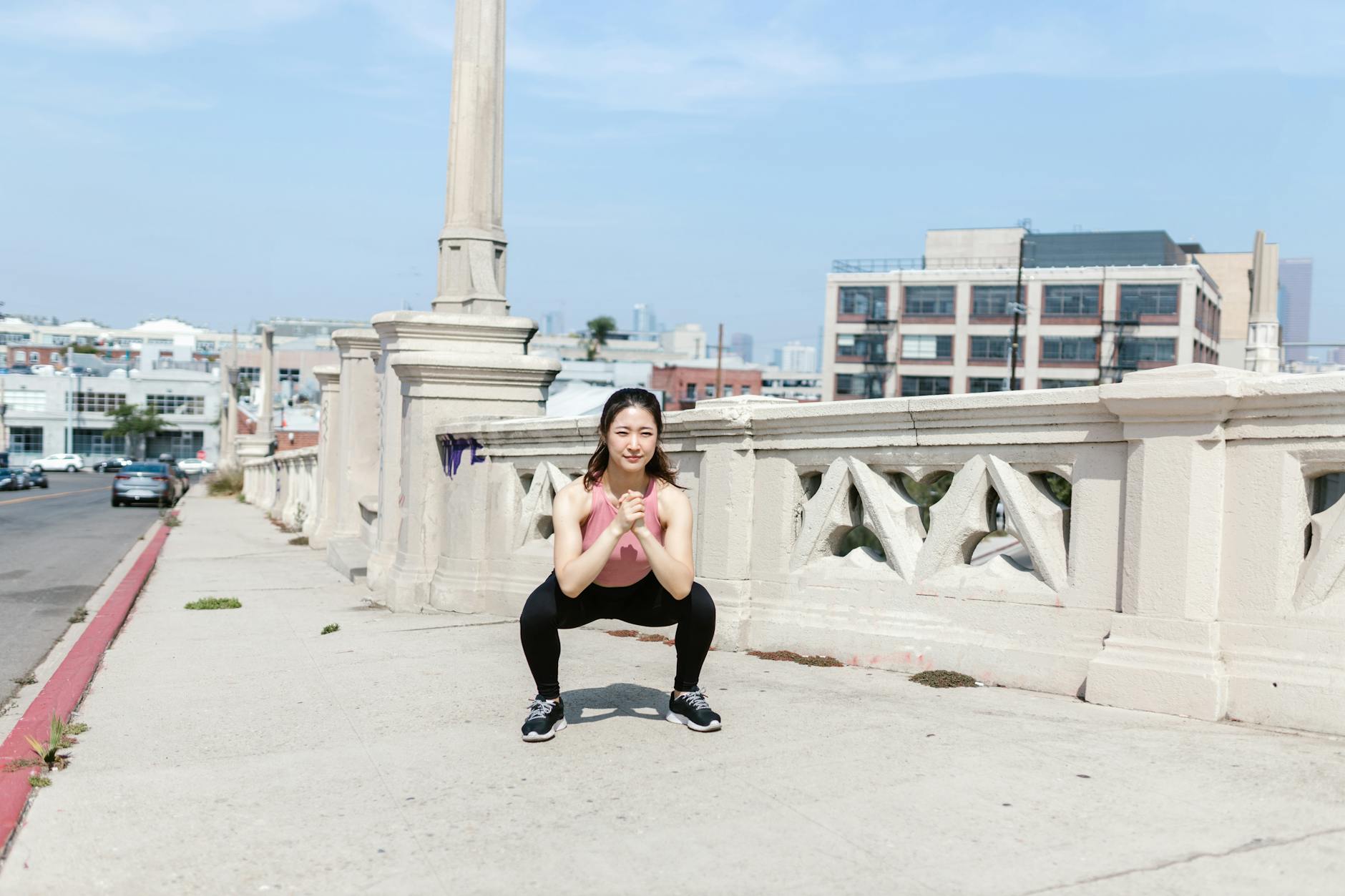 Woman exercising outdoors, performing squats on a city sidewalk. - daily workout plan