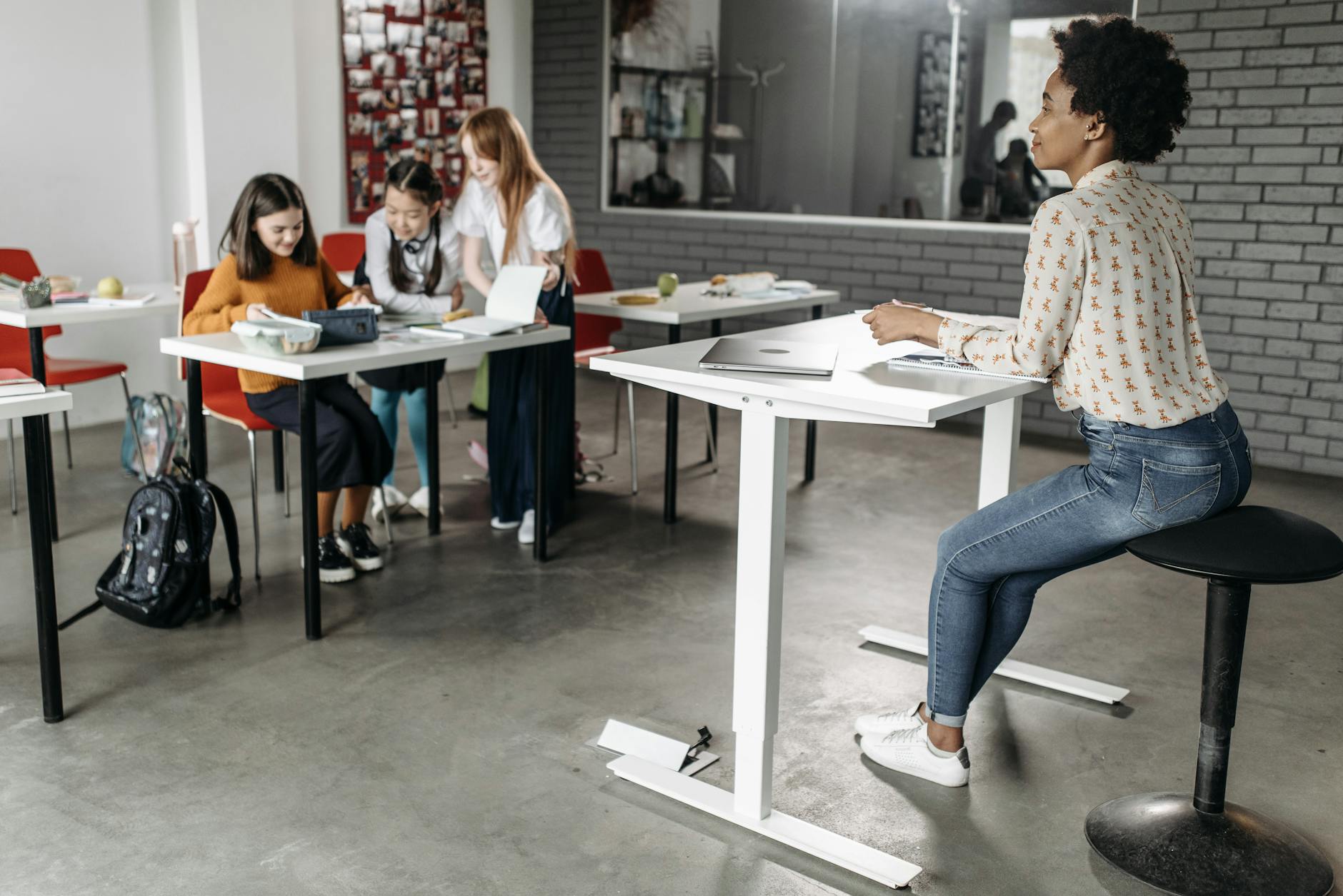 A diverse group of students engage in classroom learning with a teacher present to guide their studies. - desk exercises