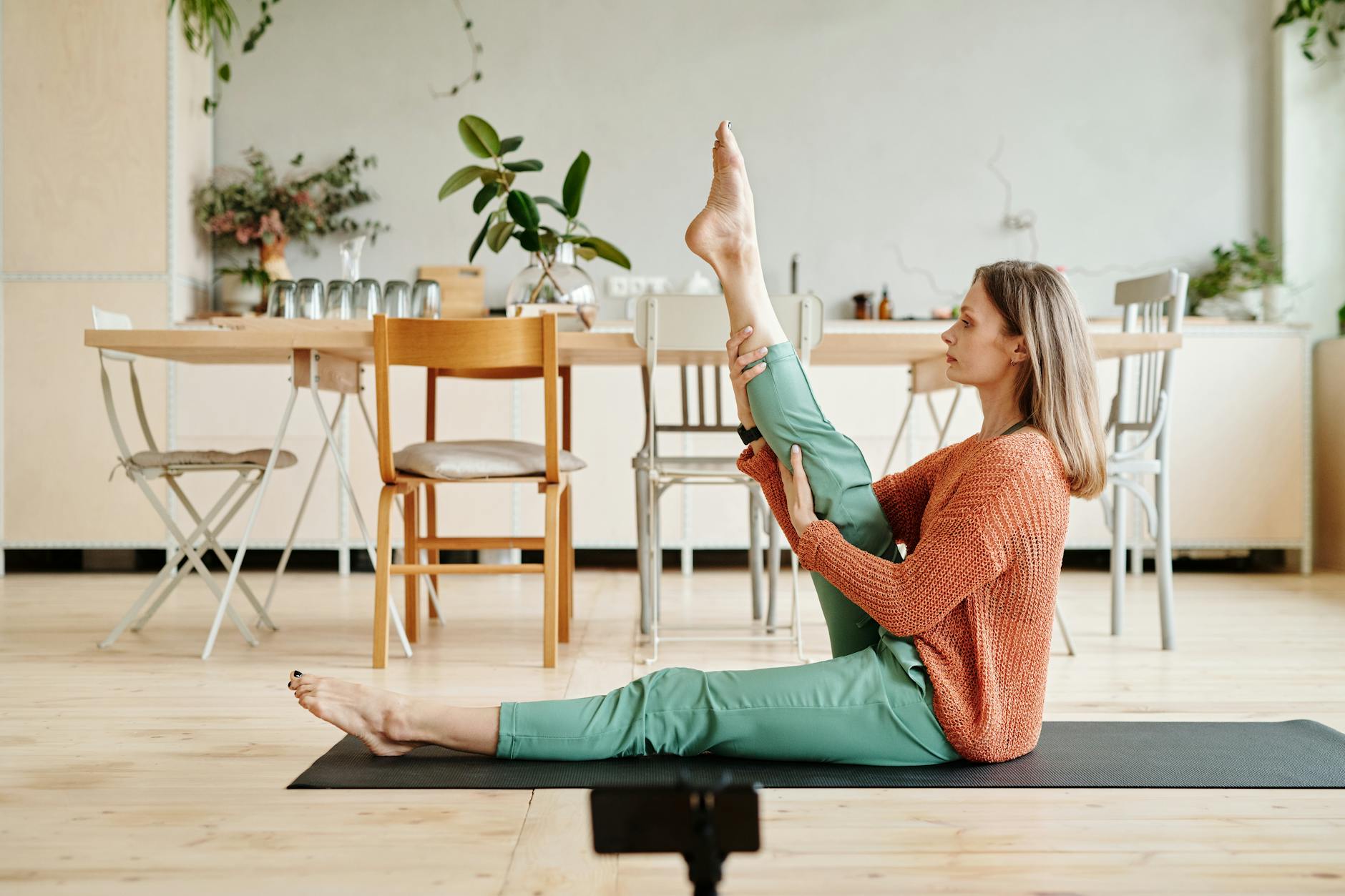 A woman performing a yoga stretch at home, surrounded by modern furniture and plants. - desk stretches