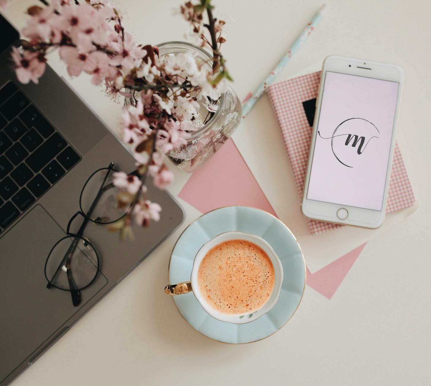 Chic workspace featuring a laptop, coffee, and cherry blossoms, perfect for creative inspiration. - digital declutter spring