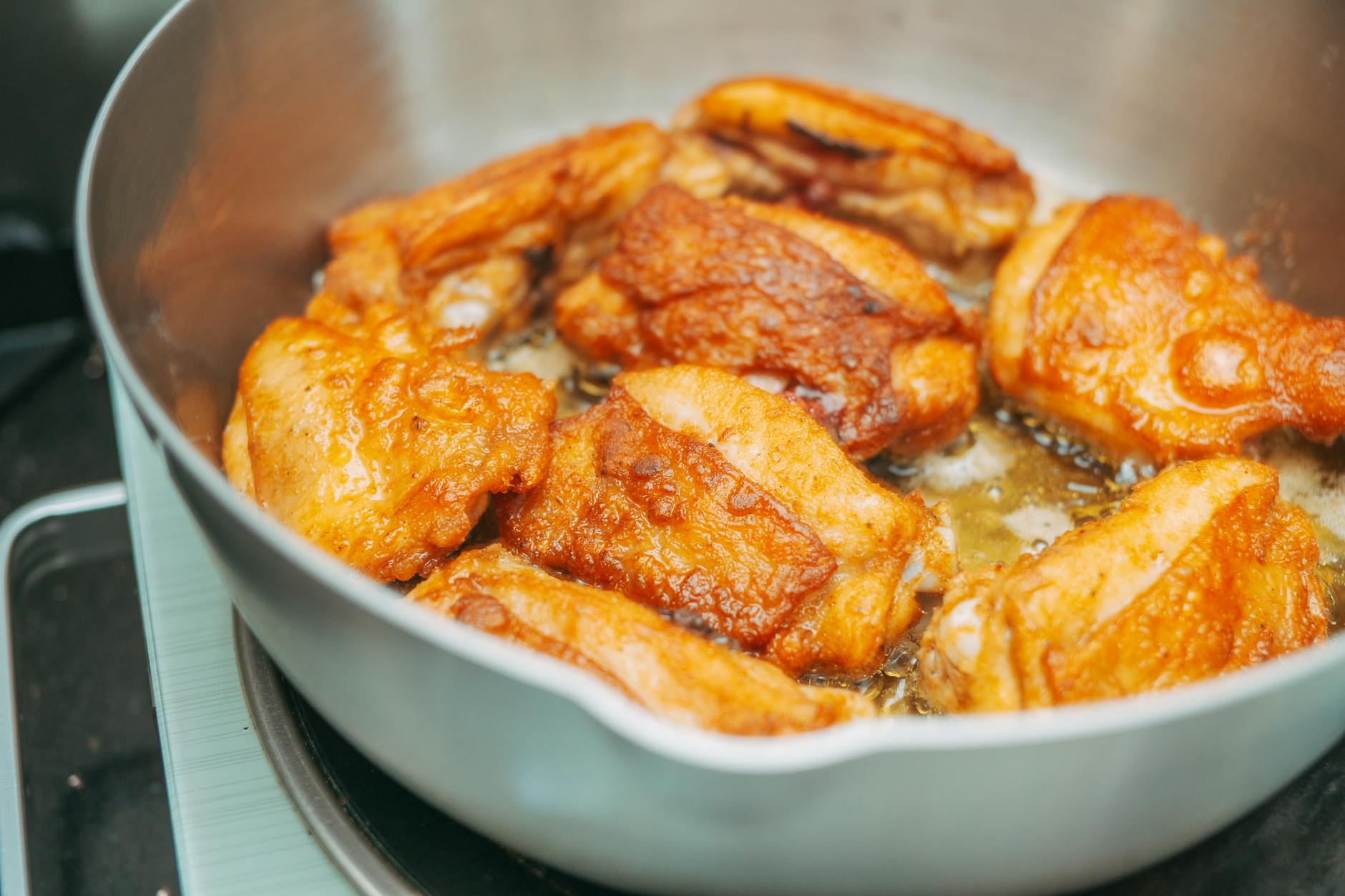 Close-up of crispy fried chicken thighs sizzling in a hot pan, perfect for meal inspiration. - easy chicken recipes