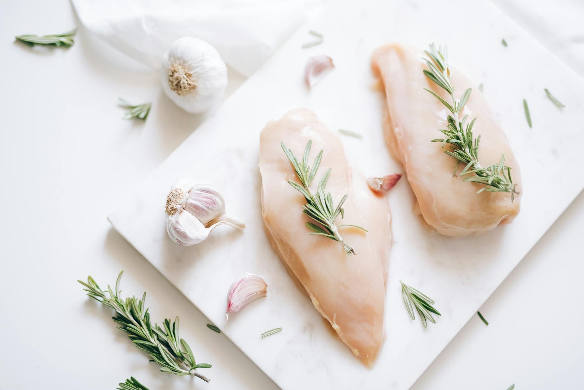 Top view of raw chicken breasts with rosemary and garlic, perfect for culinary ideas. - easy chicken recipes