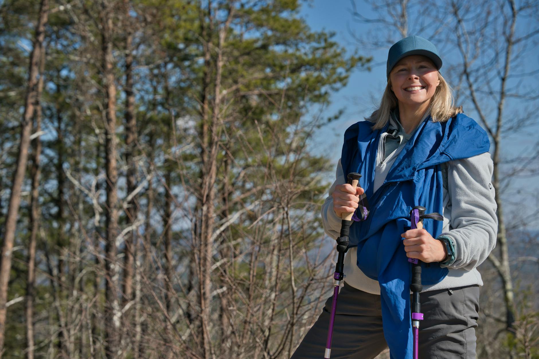 A cheerful woman trekking through Pine Mountain, Georgia, with hiking poles. - easy spring hikes