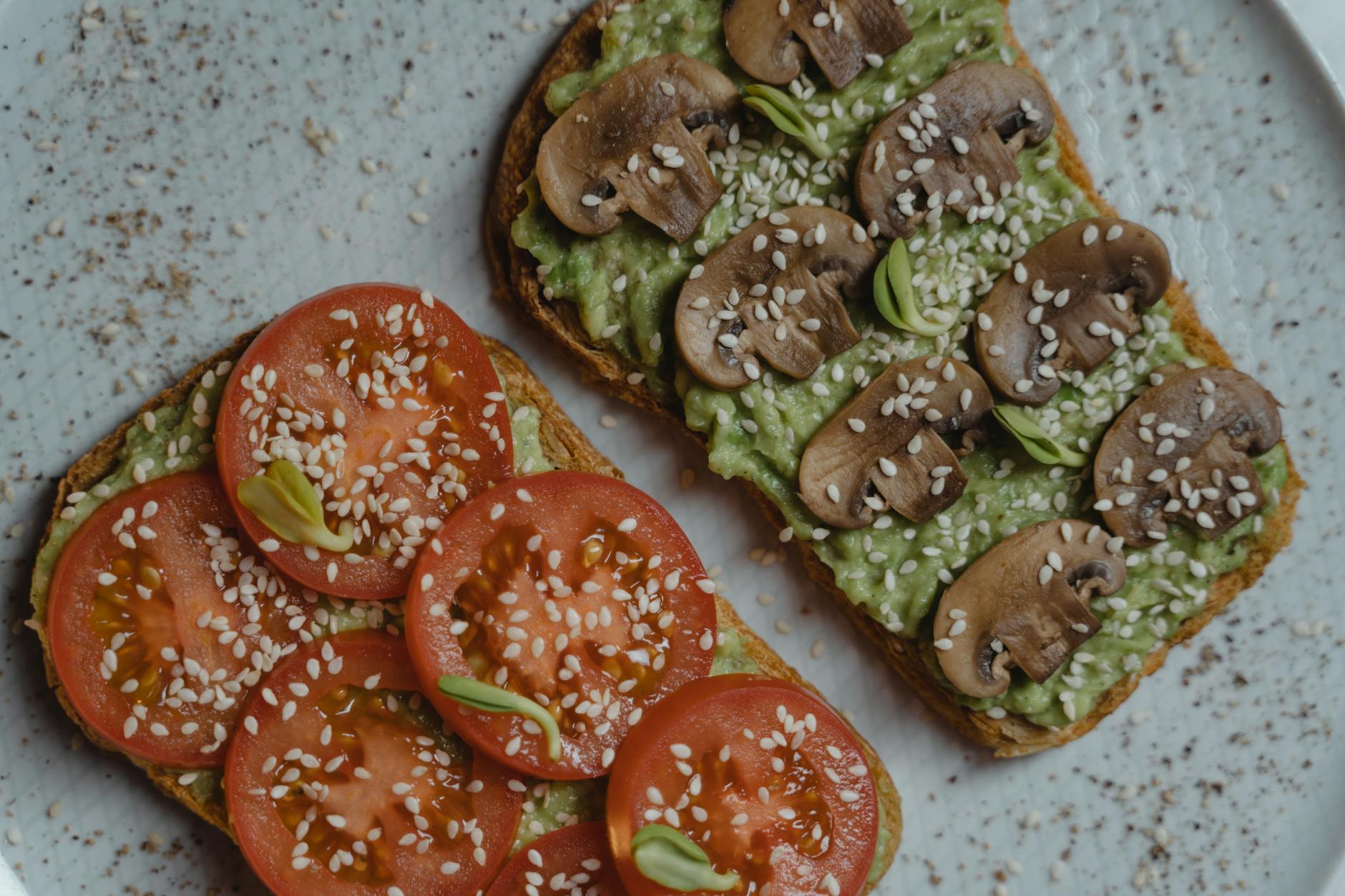 Close-up of vegan avocado toast with fresh tomatoes and mushrooms on a plate. - easy vegan recipes