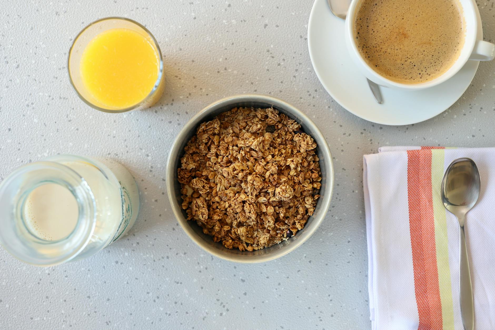 Top view of a nutritious breakfast setup including granola, orange juice, and a cup of coffee. - energy boosting foods