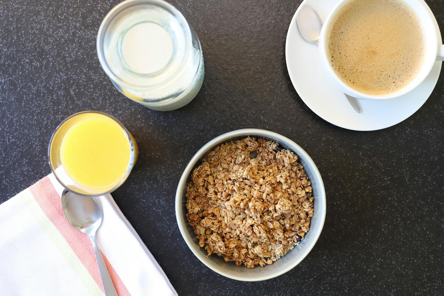 Top-down view of a nutritious breakfast featuring granola, coffee, and orange juice. - energy boosting foods