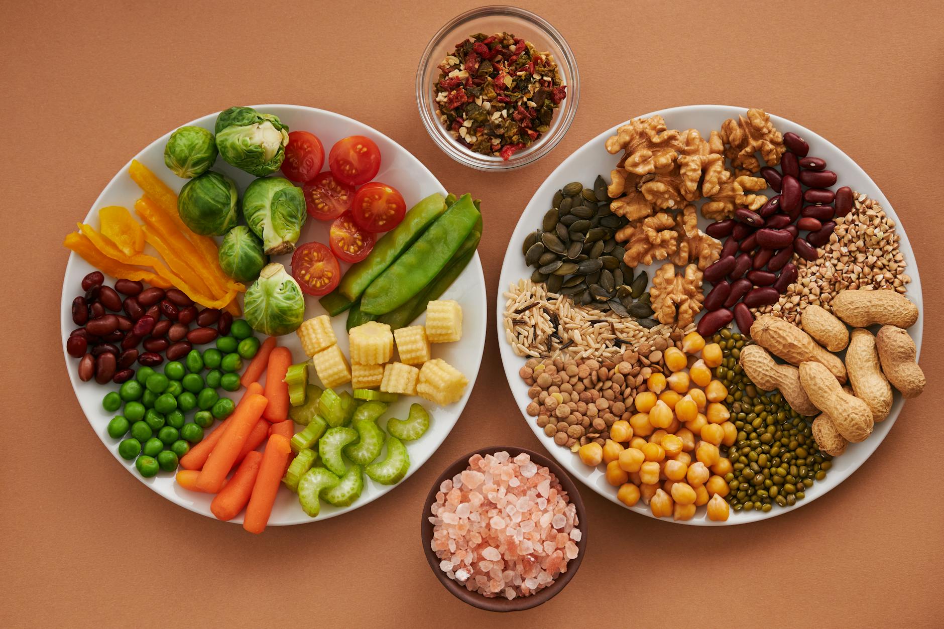 Vibrant display of assorted vegetables, legumes, nuts, and seeds on plates, perfect for healthy eating images. - fiber foods fullness