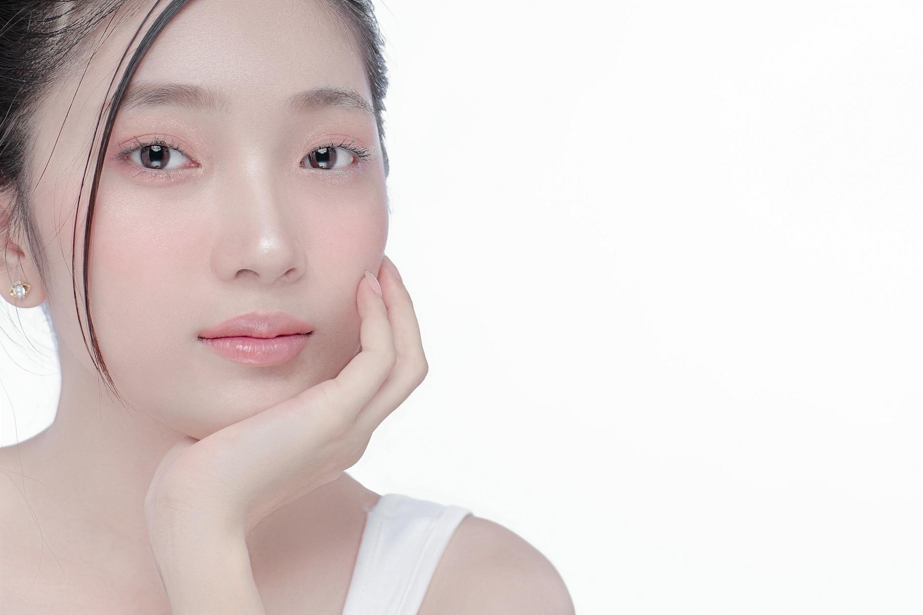 Close-up portrait of a young woman with clear skin in a studio setting, showcasing beauty and skincare. - glowing skin foods