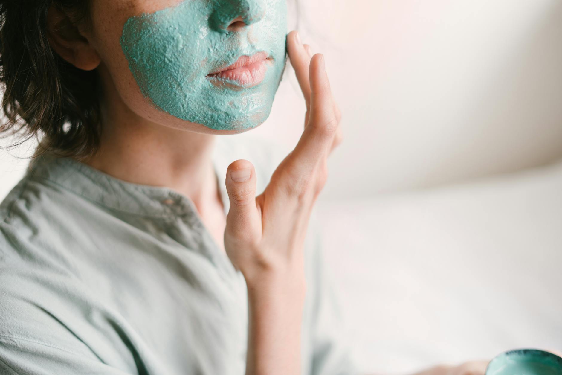 Young woman applies a rejuvenating facial mask indoors for skin care and relaxation. - glowing skin recipes