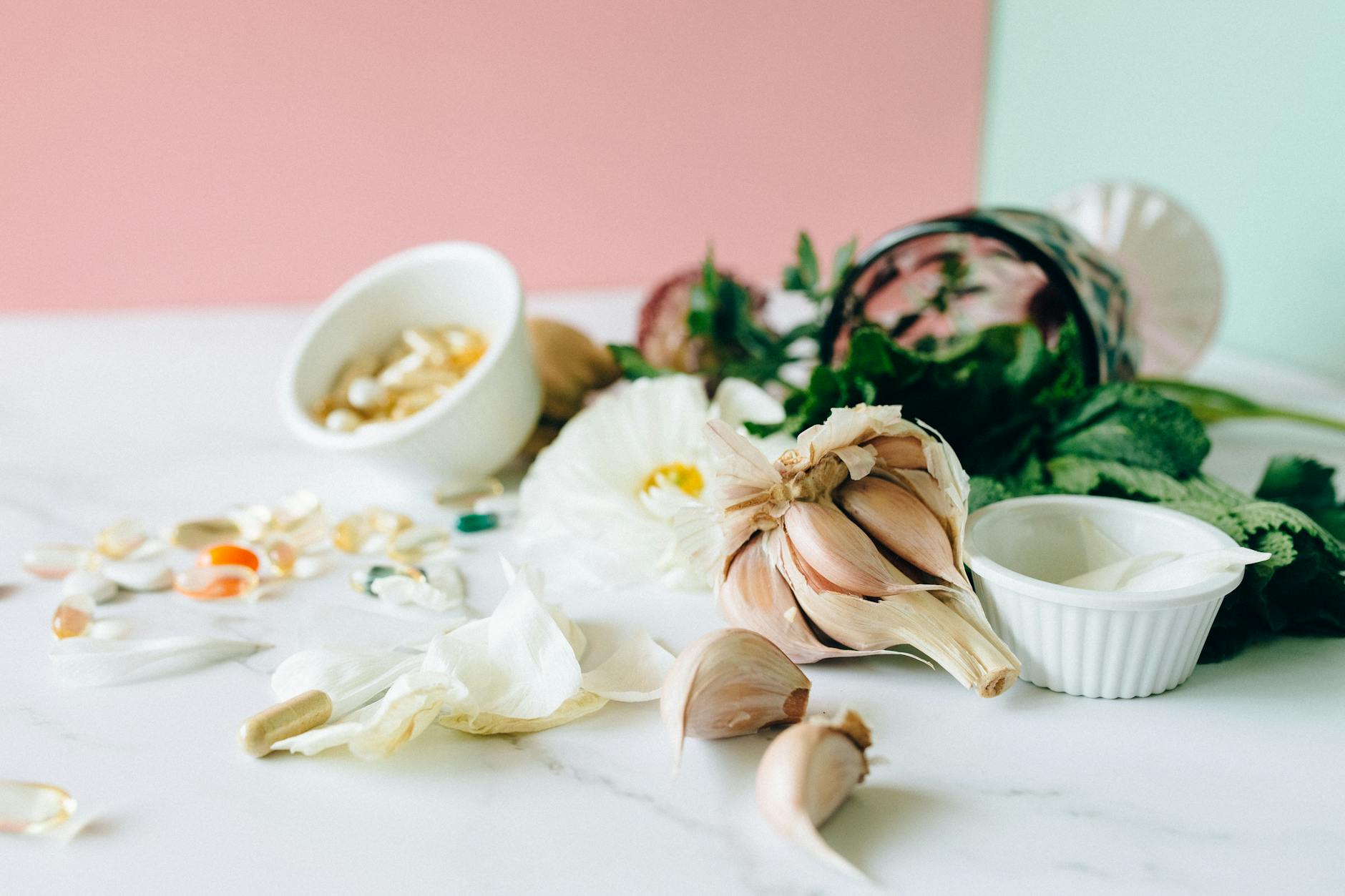 Flat lay of garlic, supplements, and herbs showcasing natural remedies on a marble surface. - gut health allergies