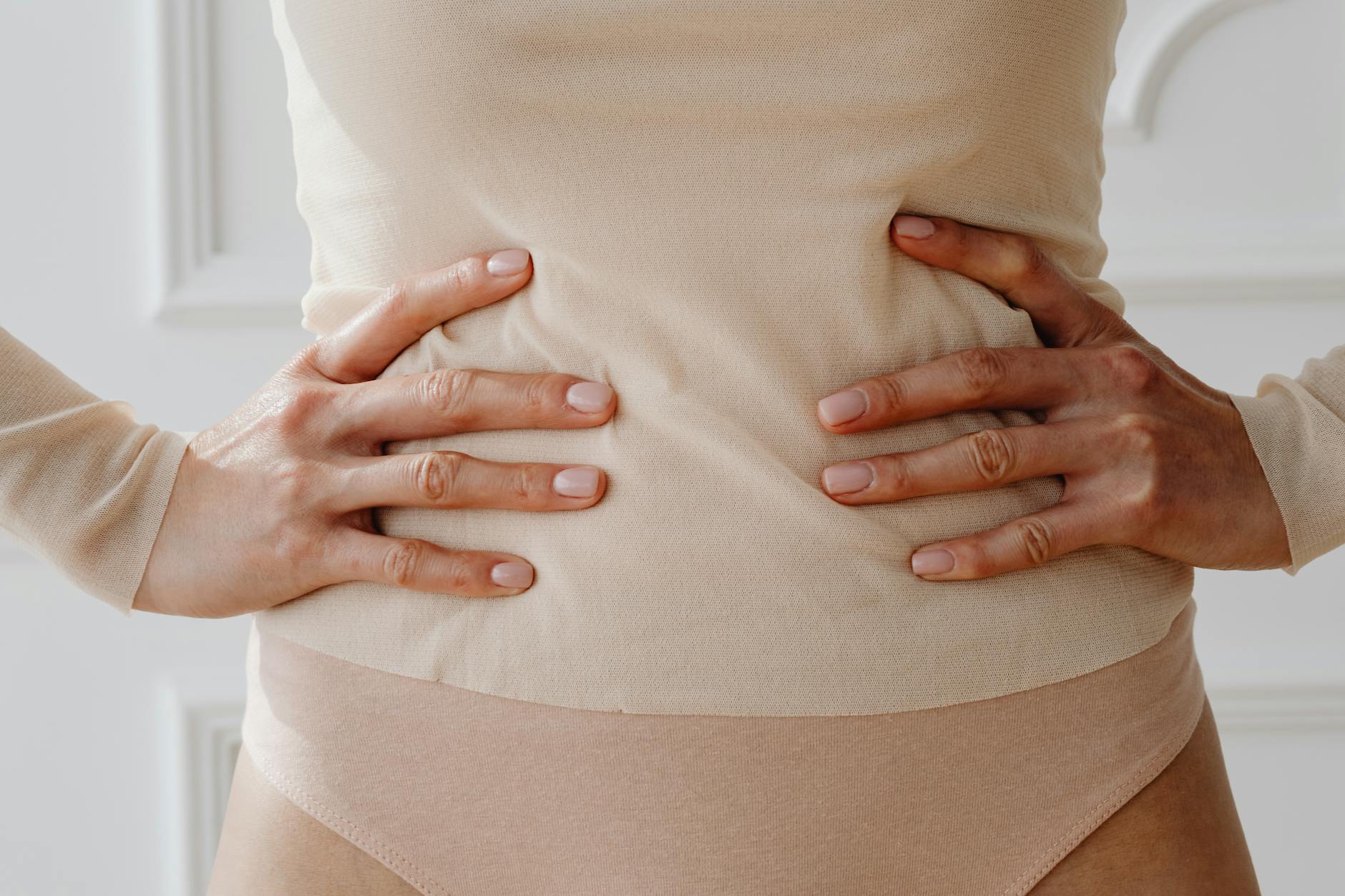 Close-up of a woman's hands resting on her waist, showcasing nude clothing. - gut health allergies