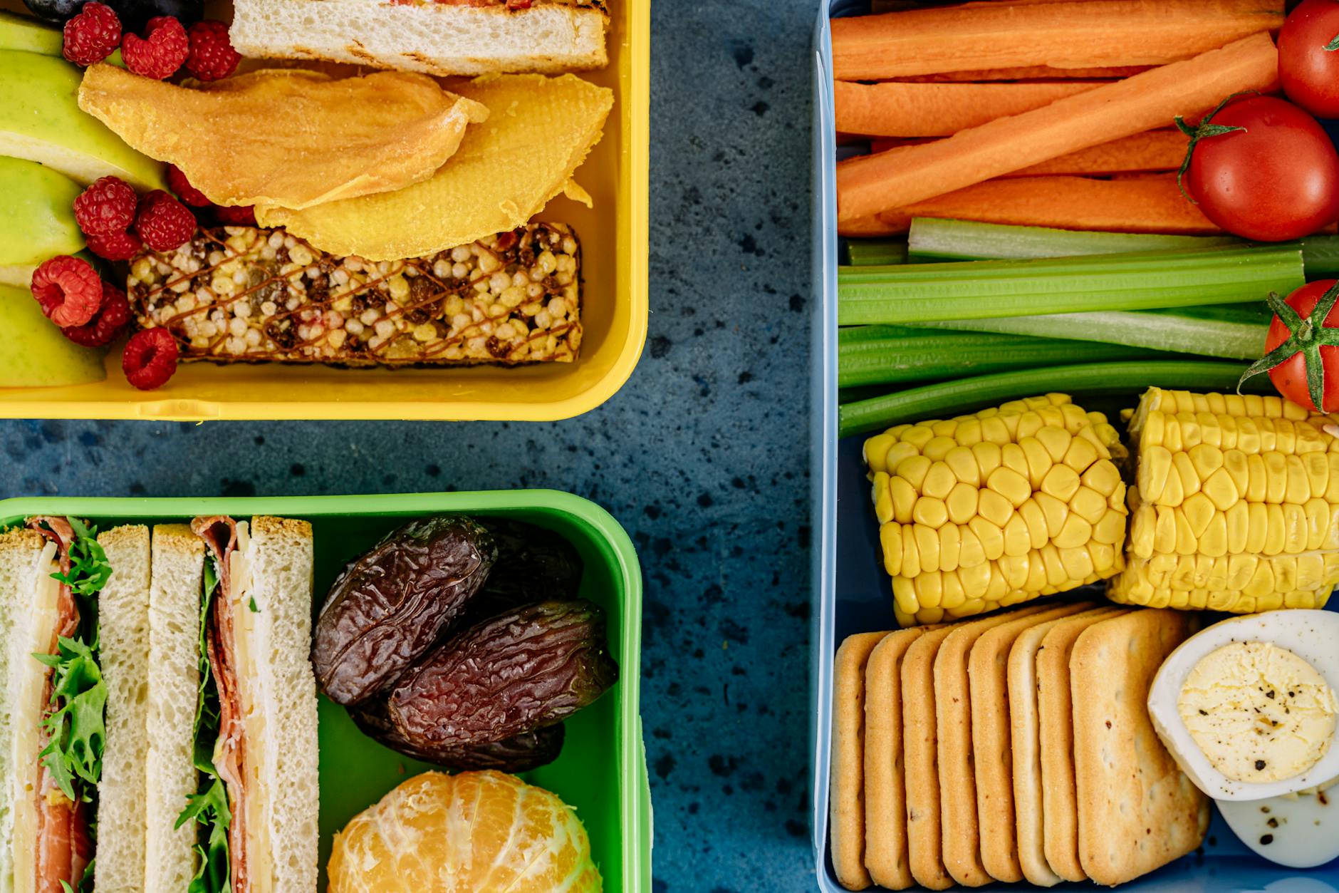 Vibrant lunchboxes packed with healthy snacks, fruits, and sandwiches presented in top view. - healthy lunch prep