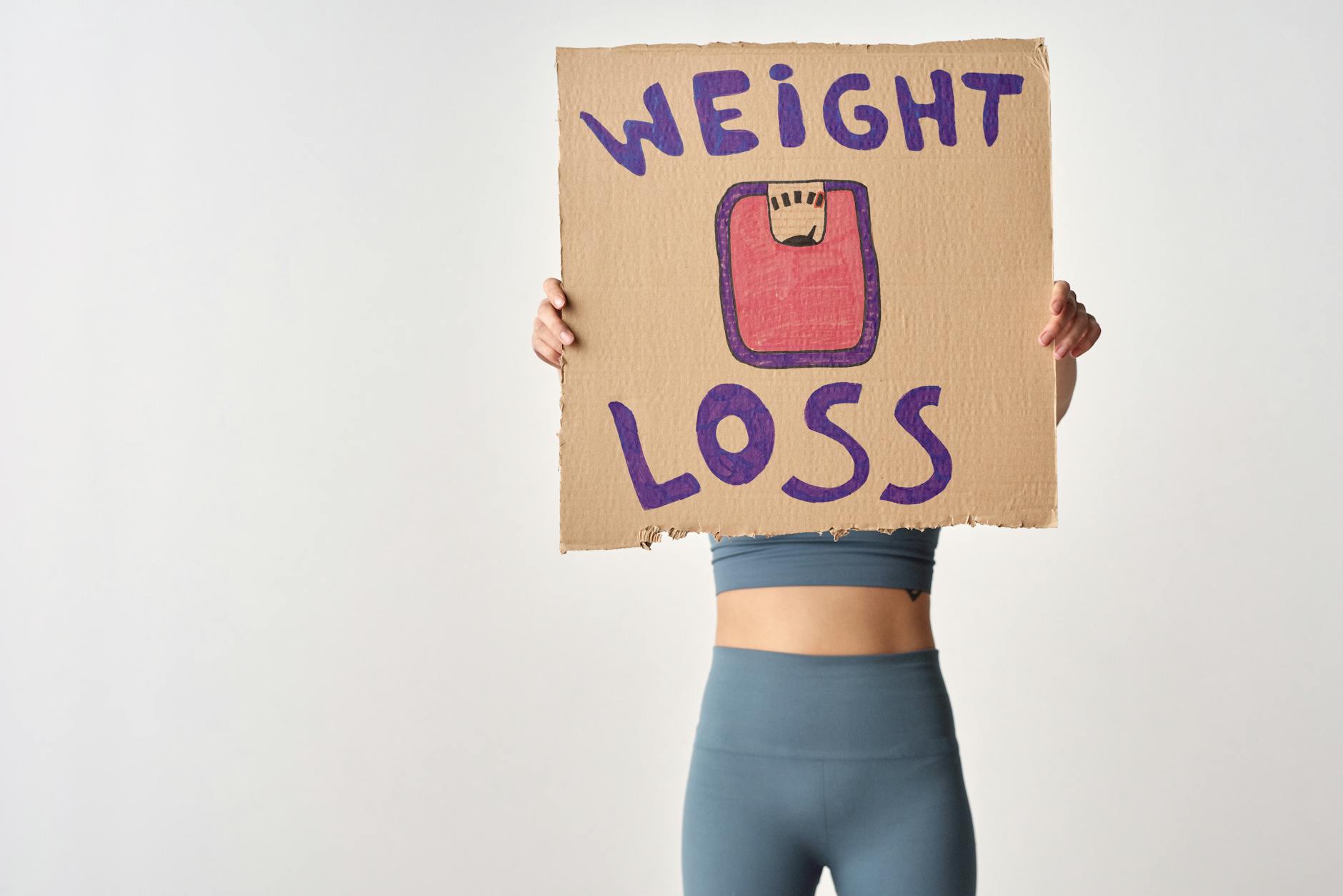 Person holding 'weight loss' sign for fitness motivation and health goals. - healthy weight loss